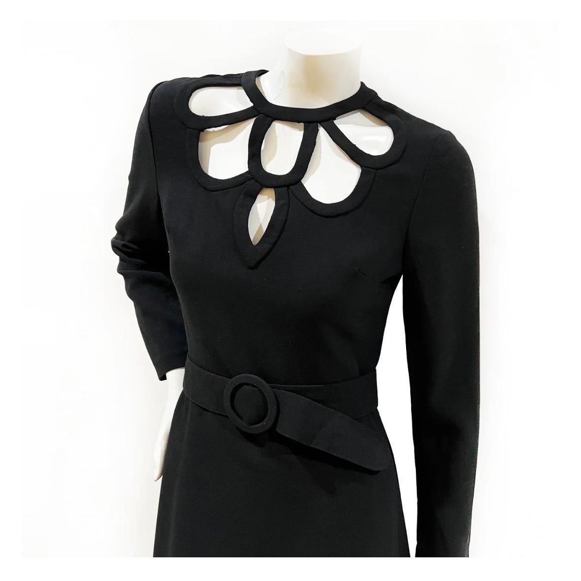 Decorative cutout neckline dress by Louis Feraud 
Made in Germany 
1974
Black 
Full-length 
Long sleeves with functional cuff zippers
Scalloped keyhole cutouts along neckline 
Includes matching belt    
Back zipper closure  
Wool blended crepe w/