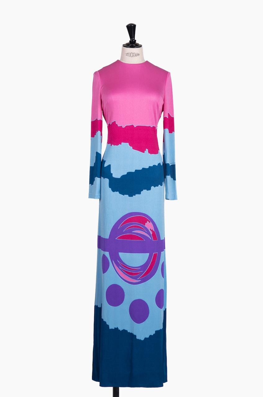This eye-catching c. 1970 Louis Féraud maxi dress shows a clashing abstract mod pattern in various shades of pink, blue and purple. It features a figure-hugging silhouette, a round neck, bust darts and long sleeves. The dress is made from a