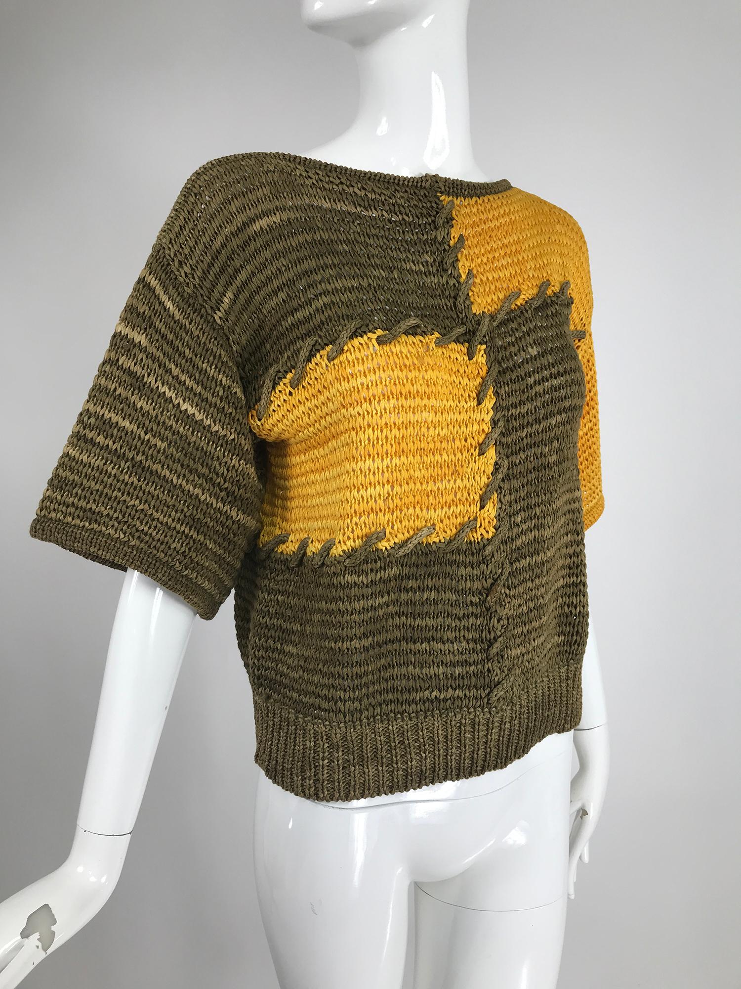 Pull Louis Feraud en tricot à rubans en vert mousse et jaune d'automne, les couleurs sont volontairement irrégulières comme peut l'être la teinture à la main. Le ruban est en tricot de coton étroit, le pull est en 100% coton. Le pull à col bateau a