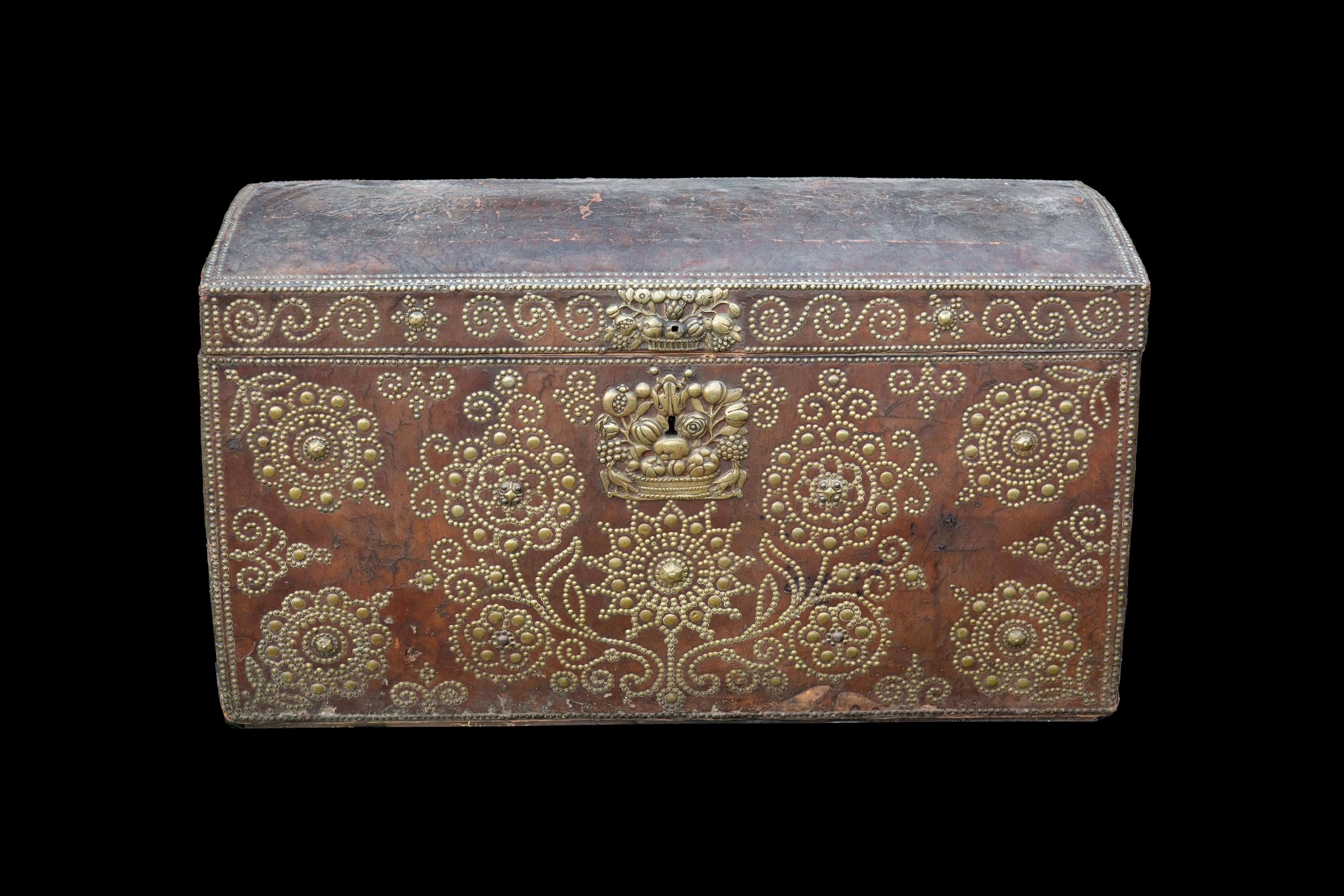 This exquisite French Tan leather travel trunk from the early 18th century presents a captivating blend of timeless elegance and meticulous craftsmanship. Adorned with brass studded decoration featuring enchanting stylized flowers, the trunk exudes
