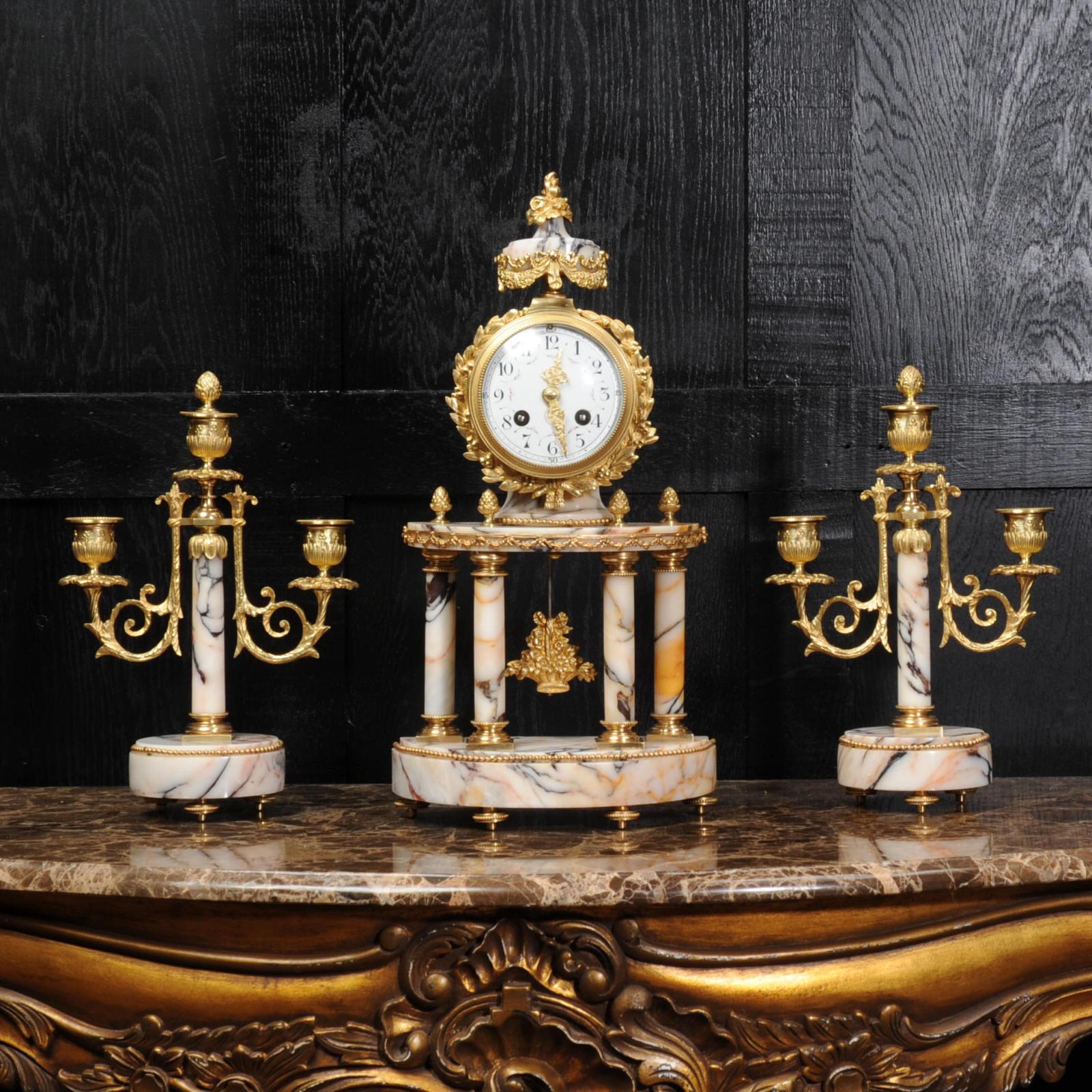 A superb original antique French clock set, fully overhauled and working, circa 1880. It is beautifully modelled in a stunning variegated specimen marble with salmon pink and silver grey veining. It is mounted with finely finished ormolu (gilded