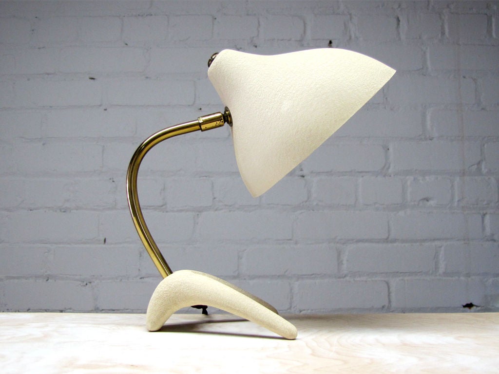 Elegant cream colored table lamp designed by Louis Kalff for Philips, the conical shade is held by a curved brass stem on an organically shaped base, resembling a Crow's foot.