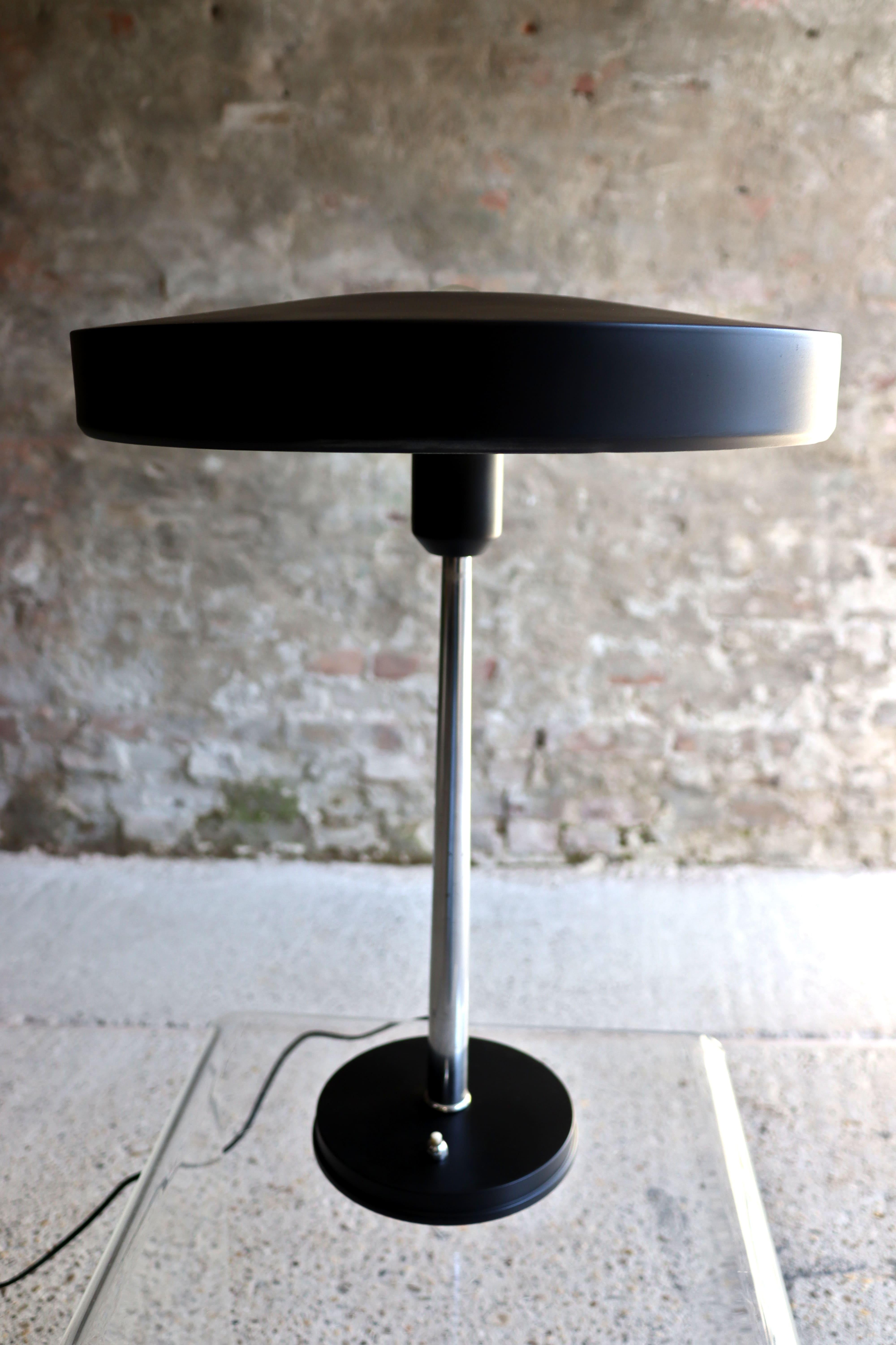 This lamp is officially called Major, but some people know it as Timur. This lamp is designed by Louis Kalff for Philips in the 1960s. The base and shade are made of black lacquered metal and the silver shaft, a characteristic detail of the lighting