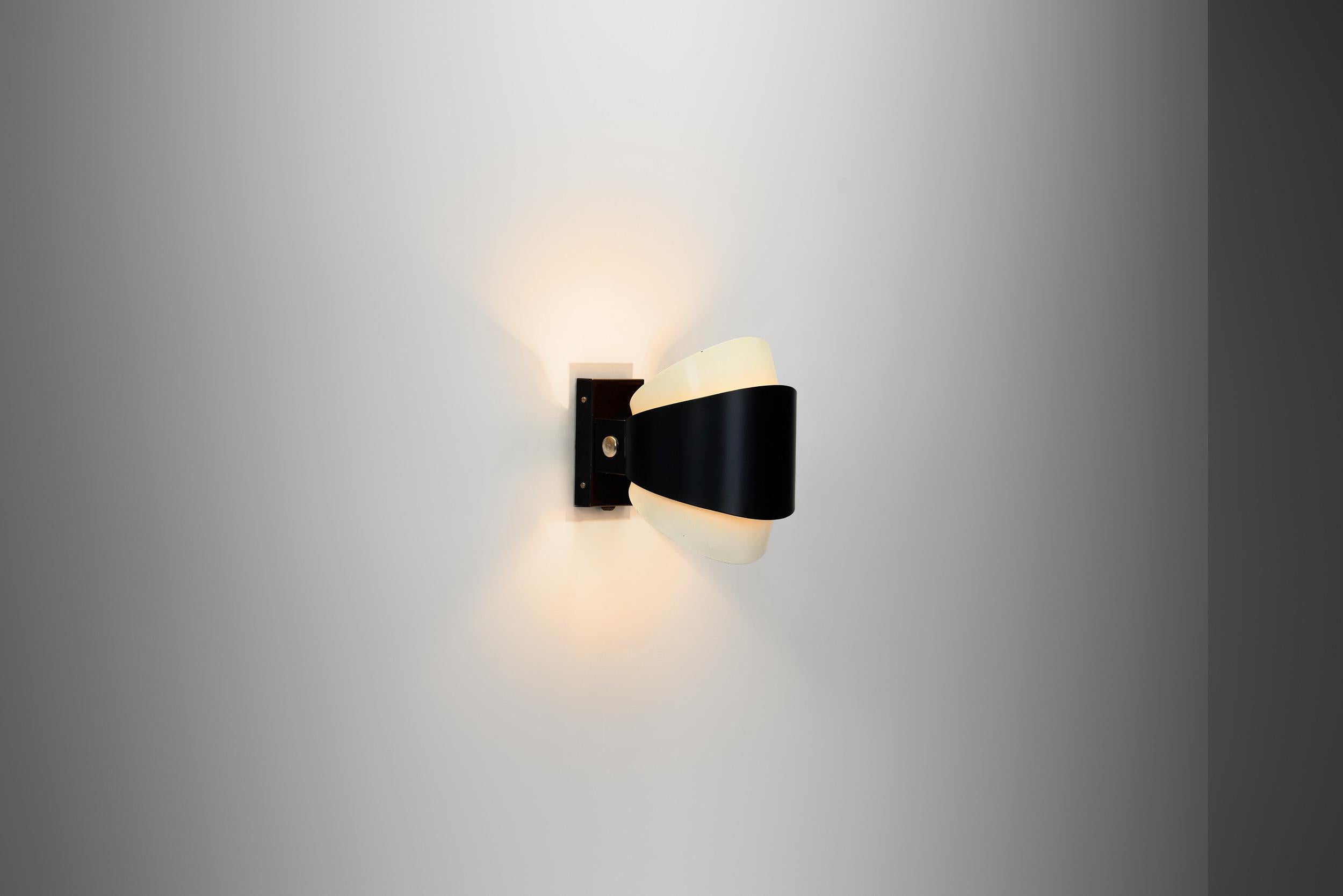 Questa lampada da parete di Louis Kalff è un esempio di design moderno di metà secolo che fonde materiali industriali ed eleganza scultorea. Kalff è stato una figura cardine del design olandese, noto soprattutto per il suo influente lavoro presso