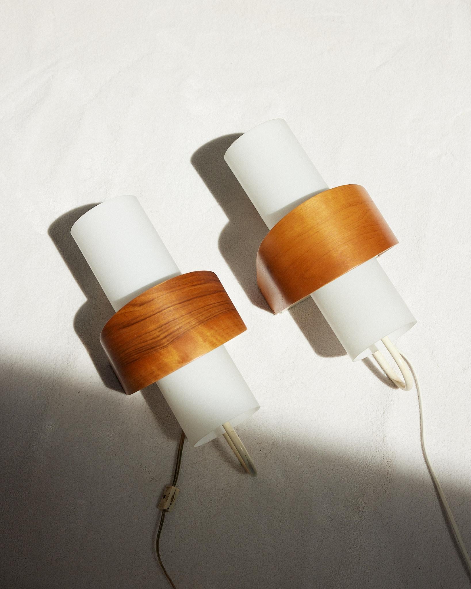 A marvellous set of Phillips wall lamps signed by the famous designer Louis Kalff in the 1950s. The lamps are a combination of metal, teak and milk glass that offers a soft light that pleasantly fills the room, creating focus and atmosphere.