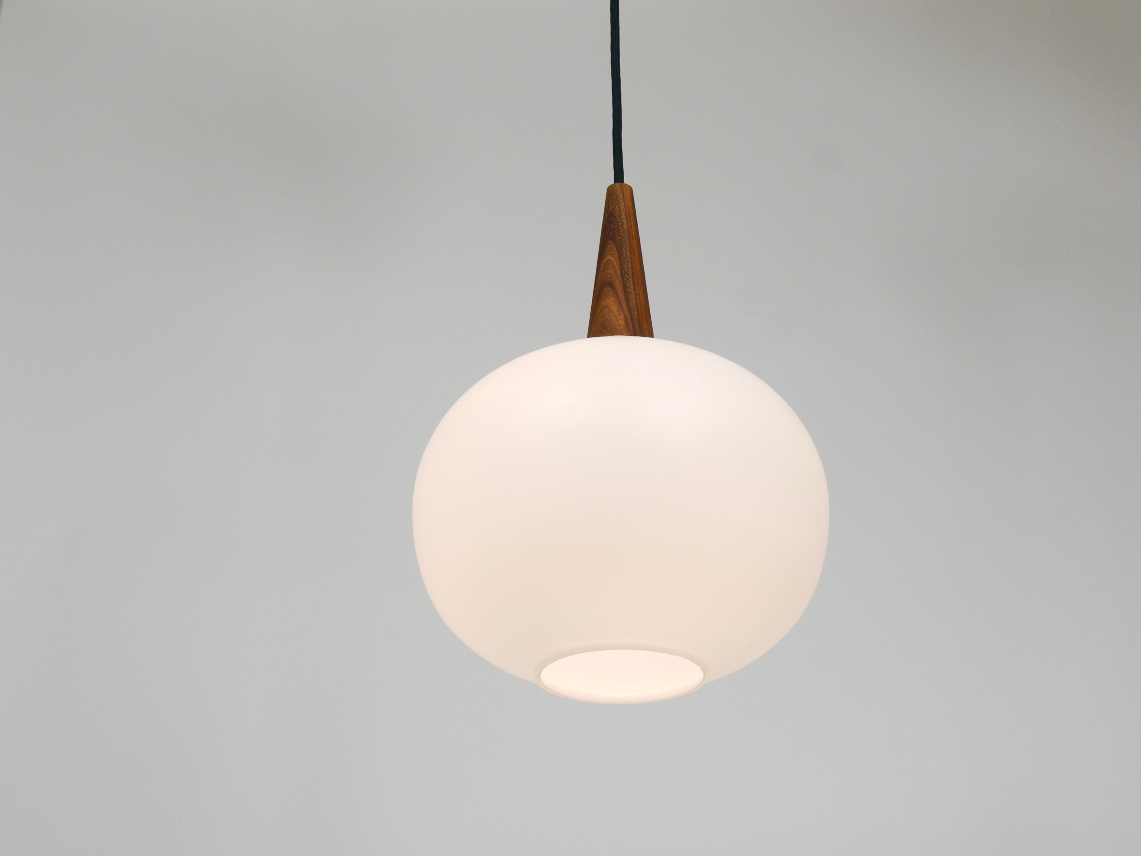 A sleek and elegant Dutch vintage pendant light dating back to the 1950s. This piece was designed by Louis Christiaan Kalff (1897-1976) for Philips in the Netherlands. The lamp features a circular satinized opaline glass lampshade topped with a