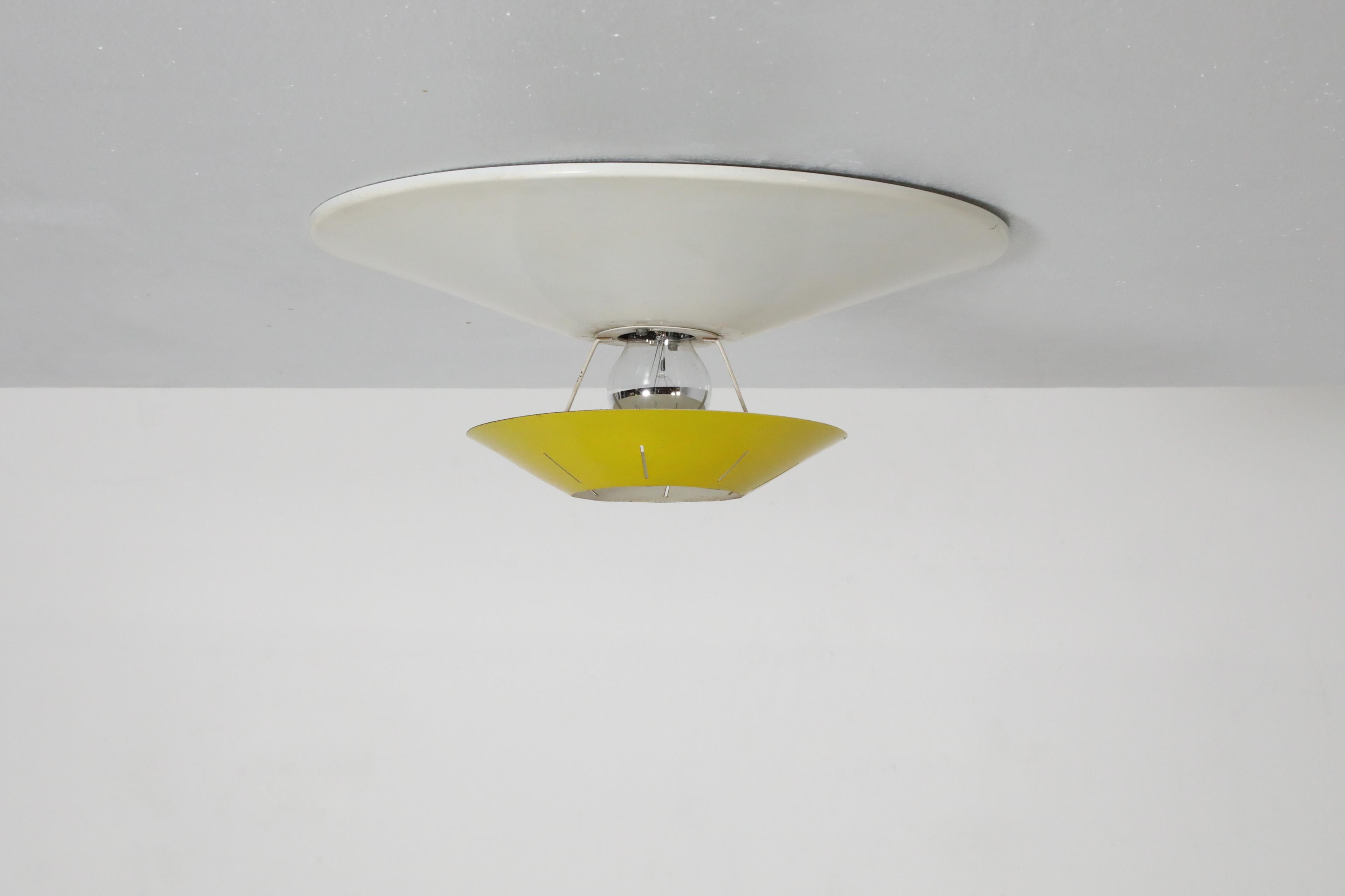 Dutch Mid-Century yellow and white enameled metal ceiling lamp designed by post-war design great Louis Kalff for the renowned Philips company.  The light has a white enameled metal base is flush mount and the smaller sunshine yellow circular shade