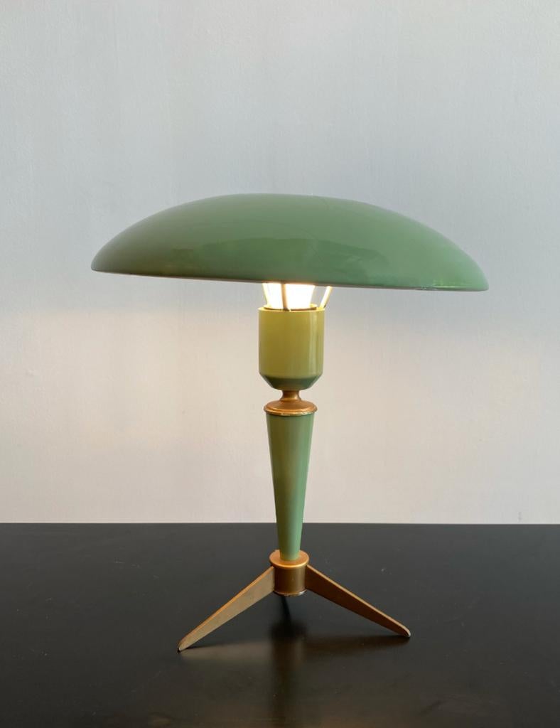 This Classic green enameld 'Bijou' table lamp was designed by Louis Kalff for Philips in the 1960s. It’s mushroom shaped body standing on a brass tripod. The subtle light is reflected upward and downward creating a balanced illumination. The desk