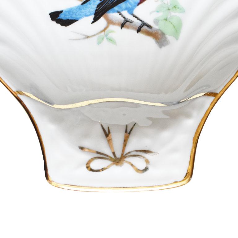 A petite porcelain trinket dish or catchall by Louis Lourioux. Crafted from fine porcelain, this small dish is created in the shape of a clamshell or seashell. It is crisp white and features a bluebird painted at its center. The bird is covered in