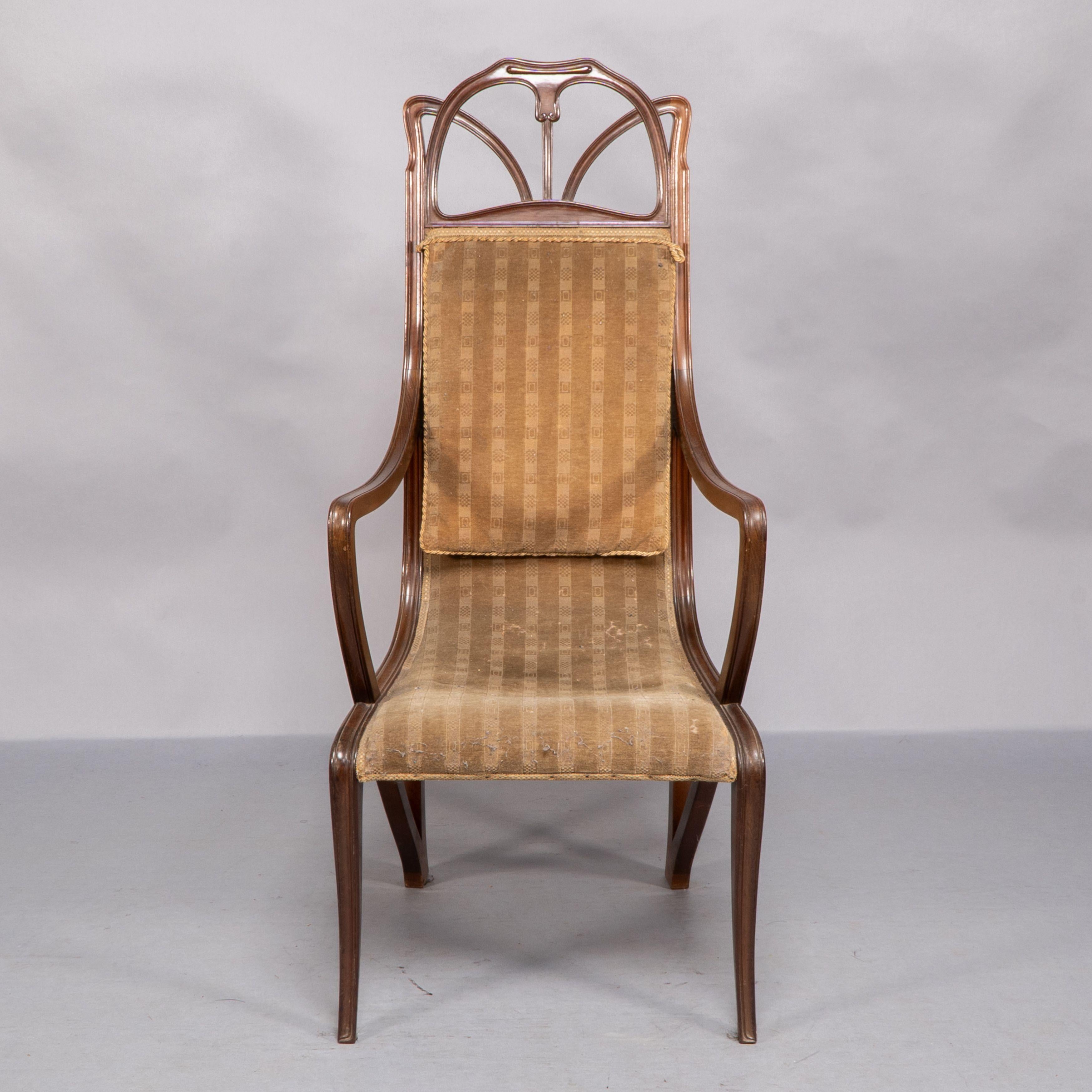 Sillón Art Nouveau de nogal tallado que conserva la tela original de la época y tiene un cojín de respaldo adicional cosido a la parte superior del respaldo.
Una ligera variación de este sillón se encuentra en el Victoria and Albert Museum de