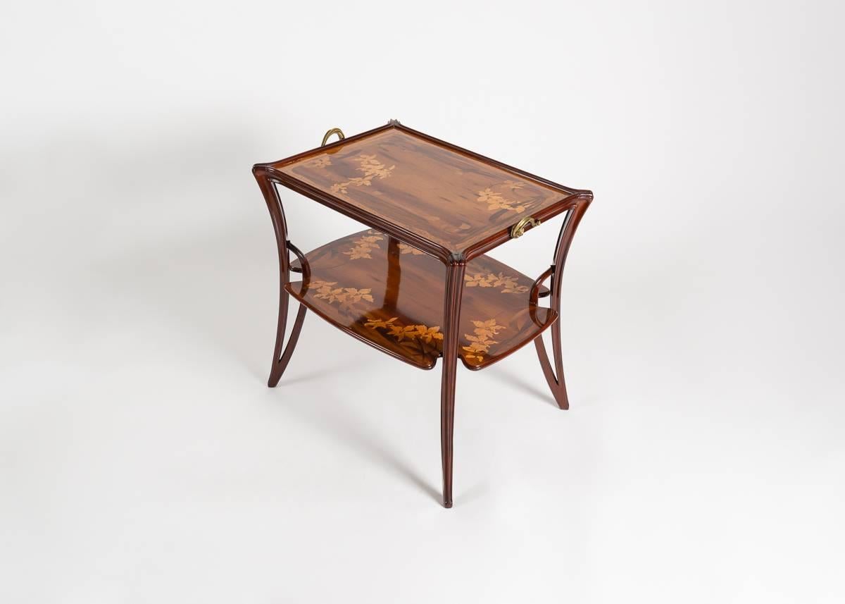 Both tiers of this remarkable fruitwood side table are decorated with an elaborate inlay depicting living matter, designed and executed by Louis Majorelle. The piece is supported by four elegantly bowed legs and accented with gilt bronze