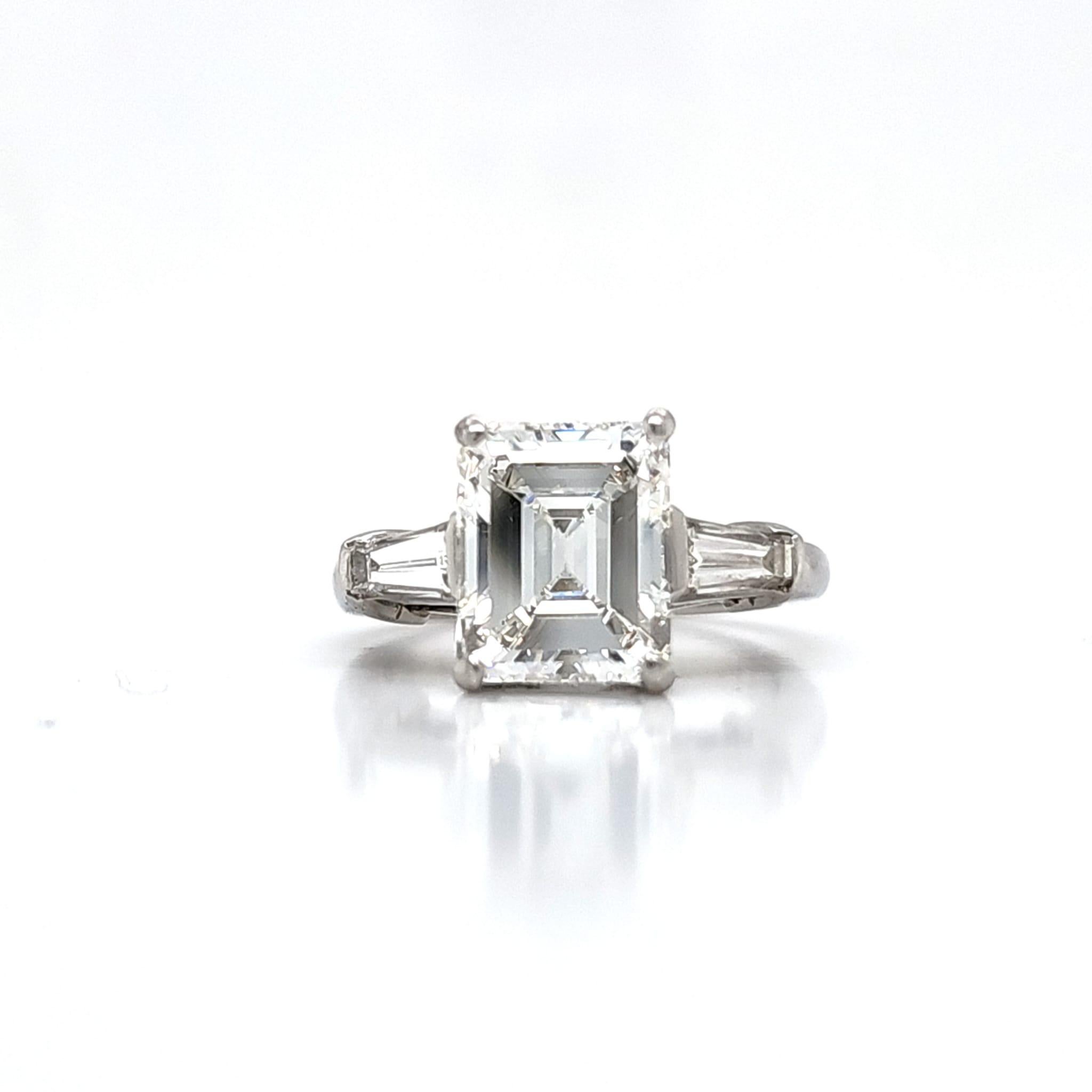 La pierre centrale est une émeraude de 3,51 carats certifiée par le GIA. Couleur G et clarté interne irréprochable (IF). La forme de cette taille émeraude est celle de l'ancienne taille émeraude, plus connue sous le nom de Tennis Court. Une couleur