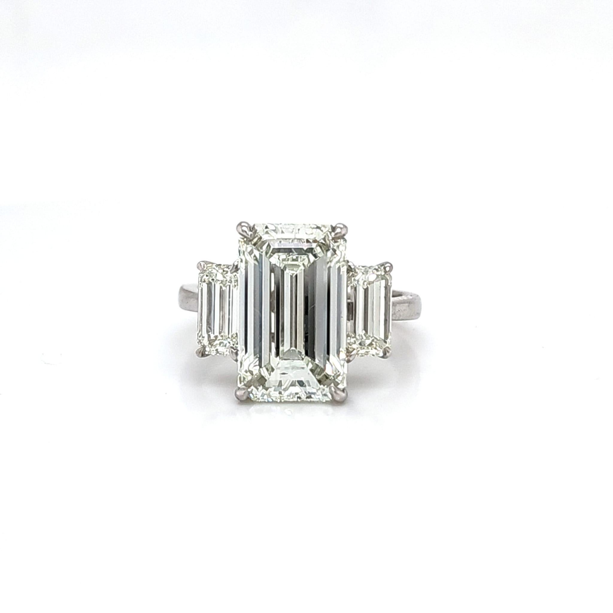 We are excited for this one! The center stone is a 5.11 Carat GIA certified Emerald Cut. K color and VS2 clarity. The center stone has a 62% depth putting it in the low depth category and has better light performance making the stone face up whiter