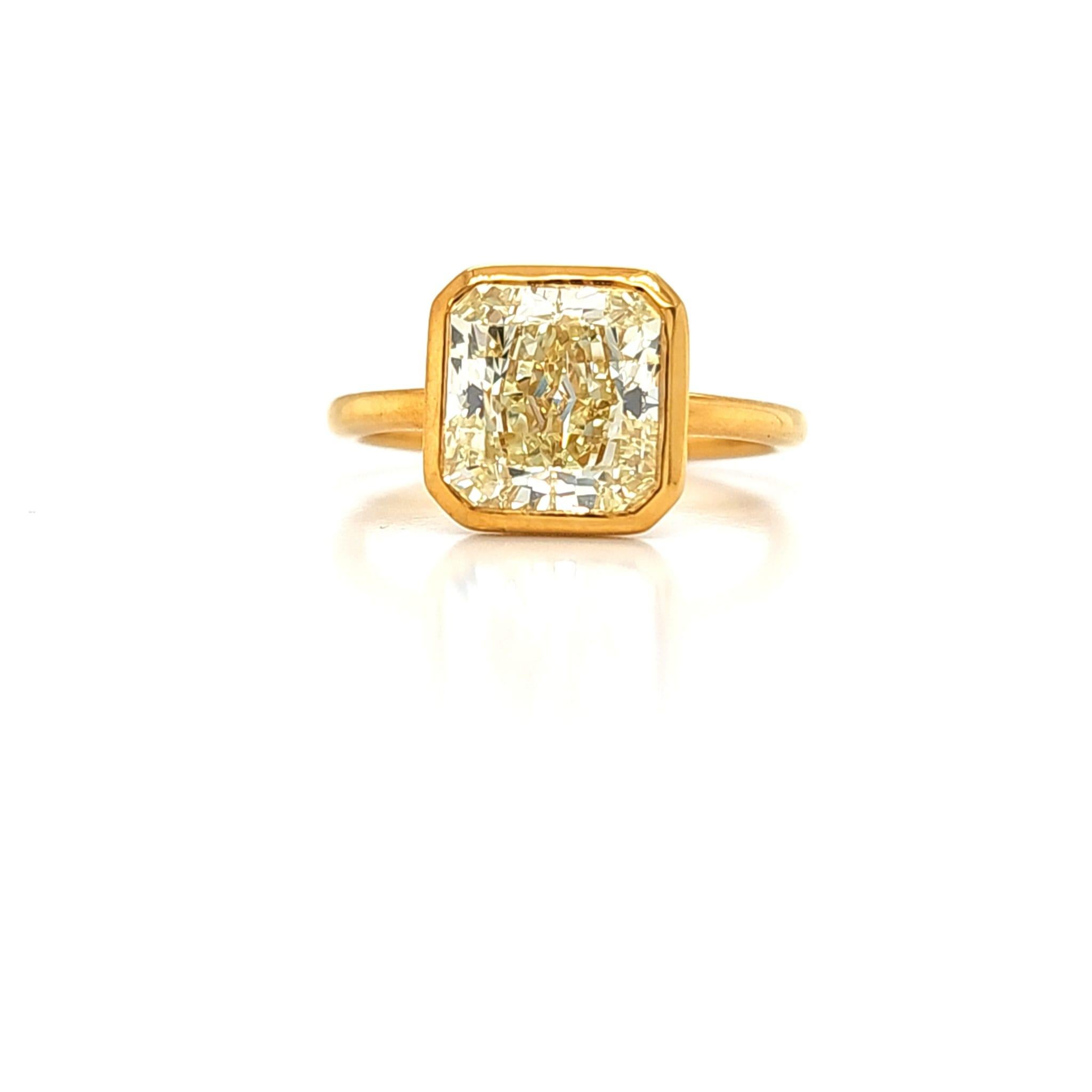 Center stone is a 3.15 carat Radiant Cut diamond that is 8.16mm in length. GIA certified W-X color and VVS clarity.  Set in an 18k Yellow gold hand made bezel solitaire setting that is dipped in 24k gold. The ring has a rich yellow tone which is