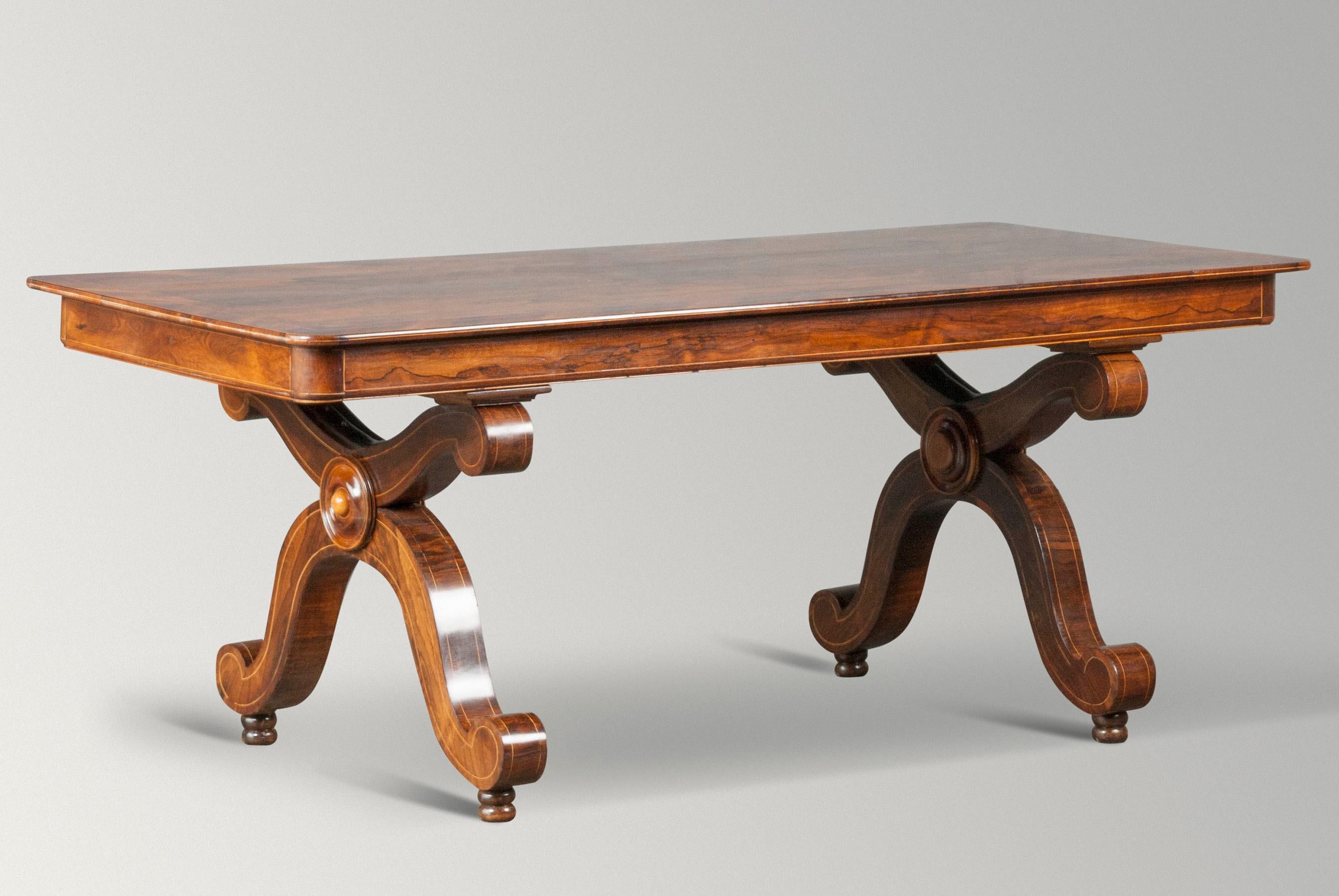 Nice antique French table or desk. Mahogany veneered, the tabletop has rounded corners and a fine edge of light wood. The table has a beautiful patina, nice warm color. The X legs are designed with decorative curls. The table is dismountable, both