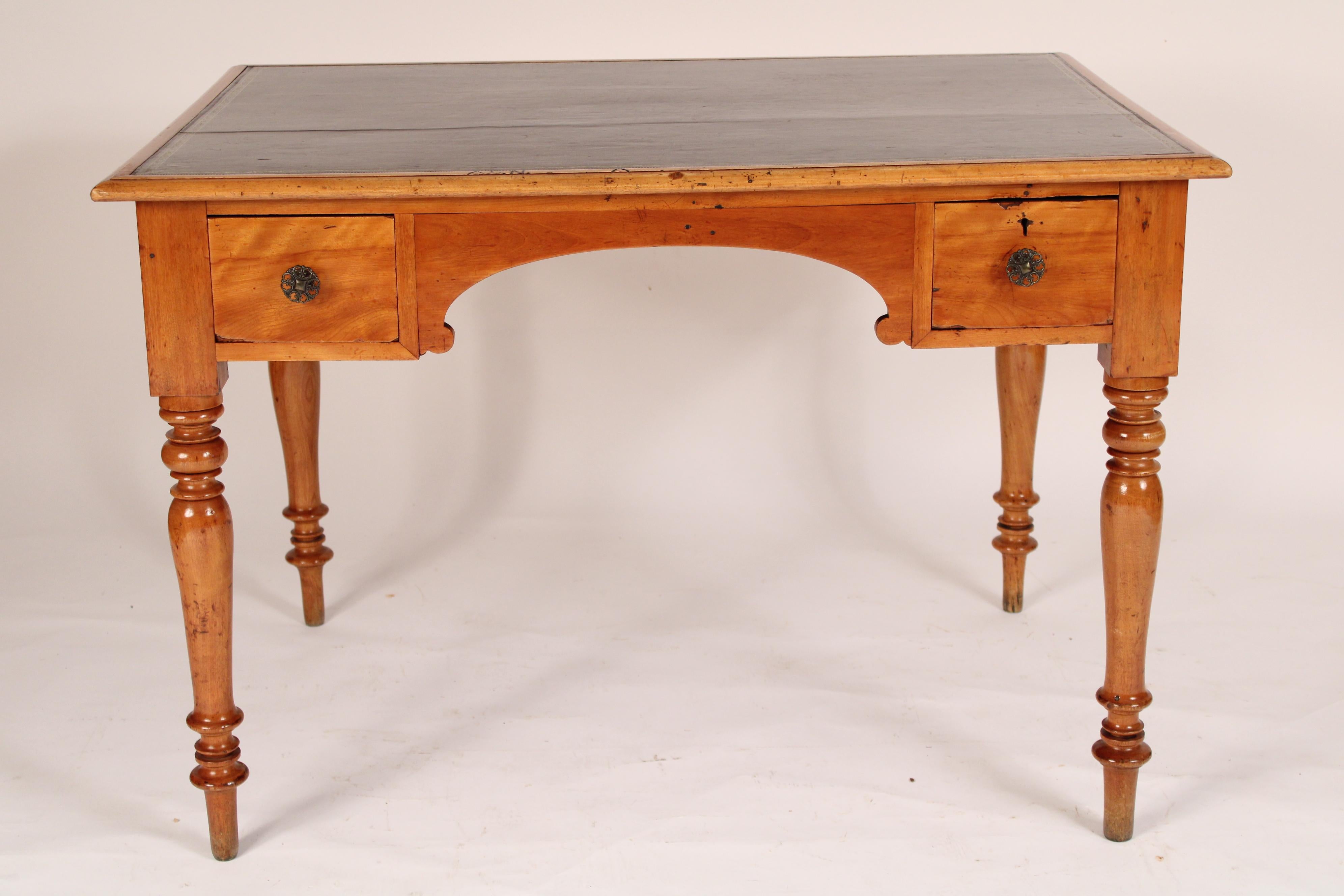 Louis Philippe birch writing table / desk with a tooled leather top, mid 19th century. With an inset tooled leather top with birch borders, the frieze with two drawers flanking an arched knee hole, resting on turned tapered legs. This desk / writing