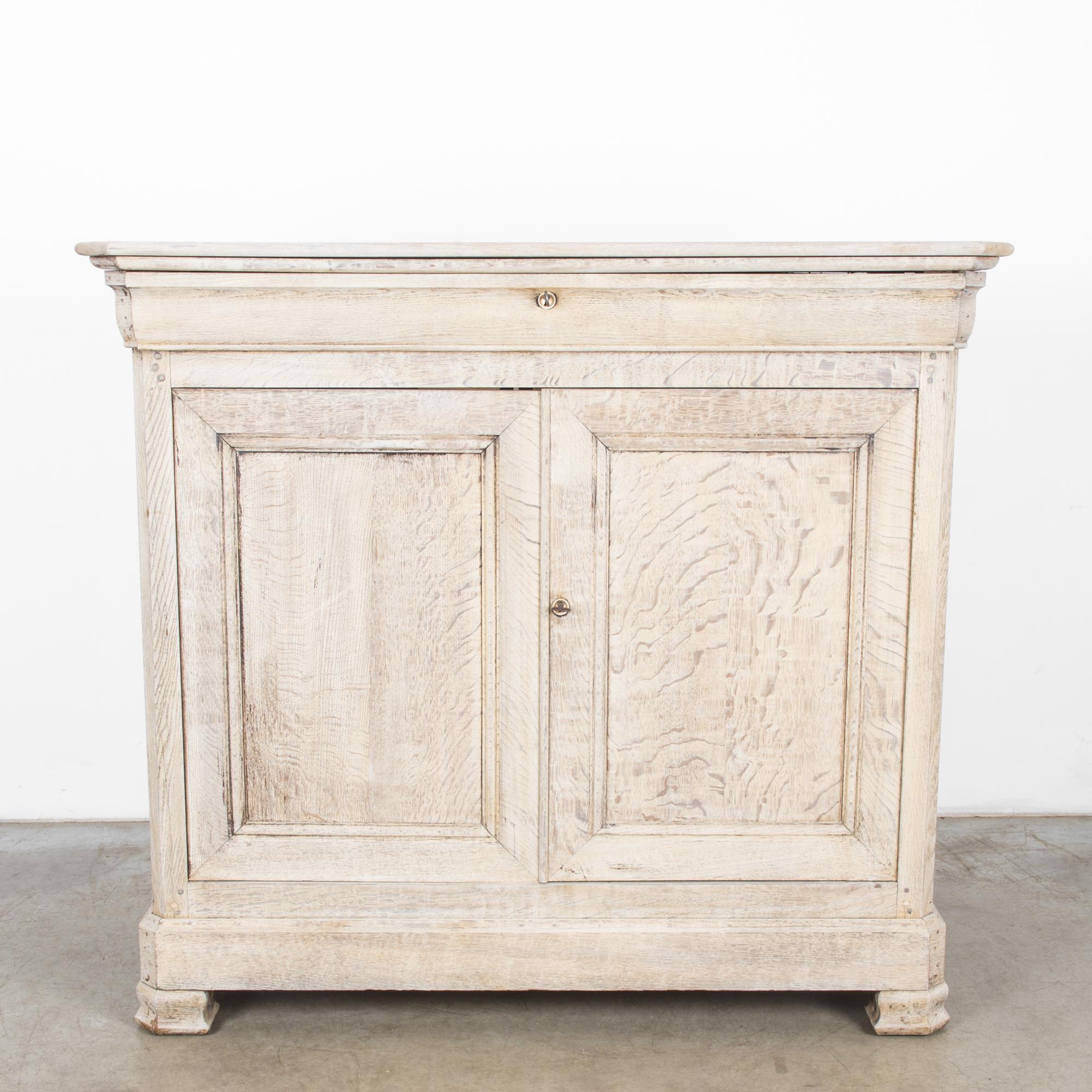 This bleached oak buffet with a stepped top was made in France, circa 1880, and brings the understated elegance of a rustic country house. The buffet consists of a long drawer above and double doors, which open to reveal a spacious storage