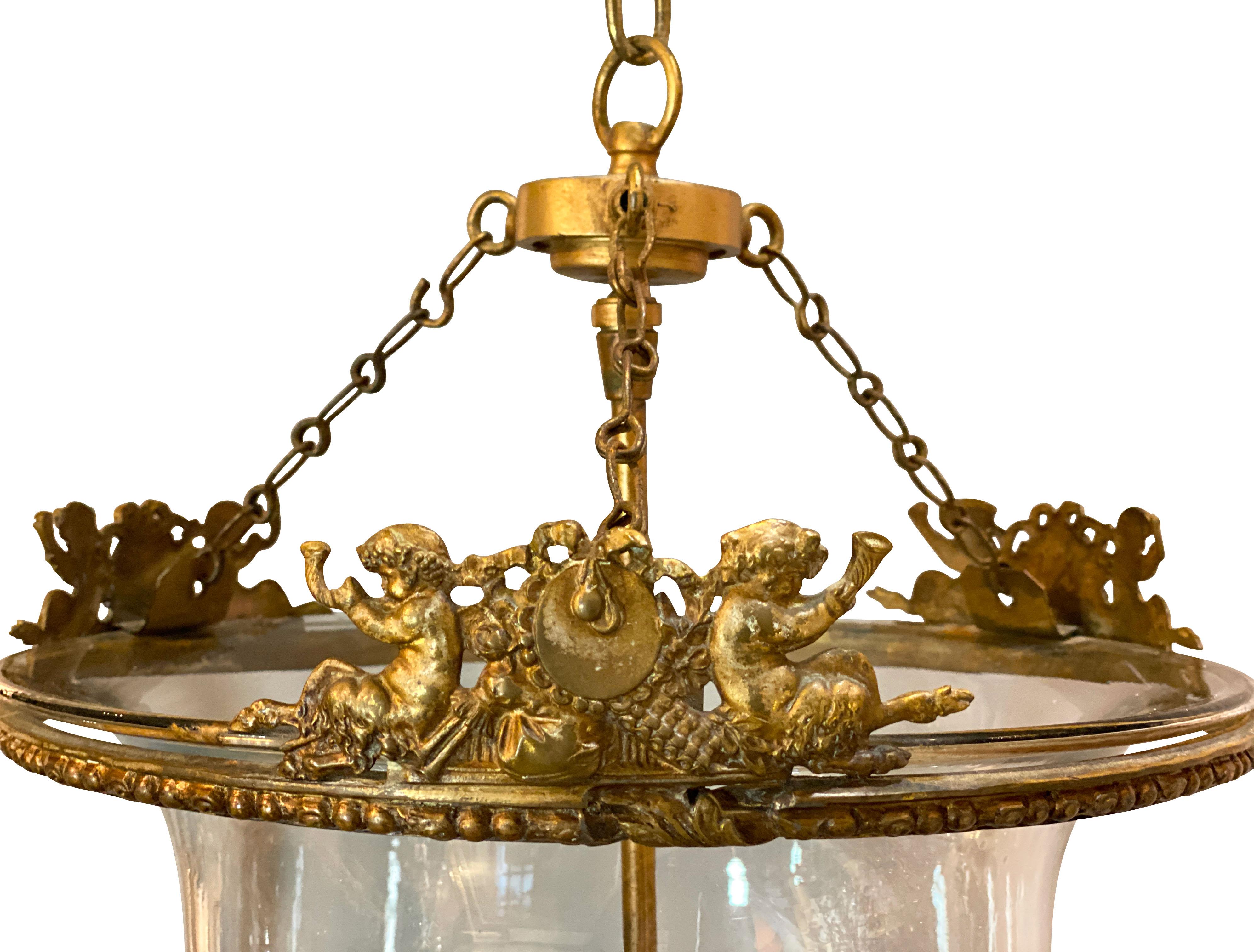 With eagle suspended clasping a ring and chain that suspends the glass jar suspended on three chains, the top gilt brass rim with fauns blowing horns in merriment.