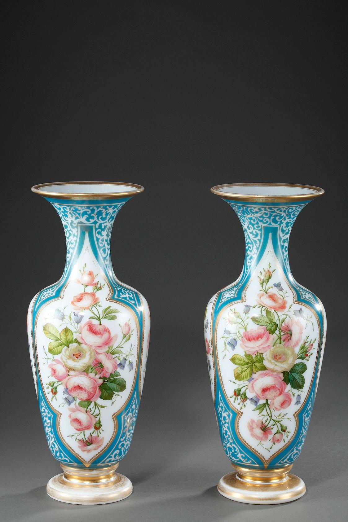 An enamel opaline baluster-shaped pair of vases decorated with polychromatic flowers in lobed cartridges on light blue background hightened with white and gilded rinceau. The base and collar are underlined with gilded stripes. Light wear to the