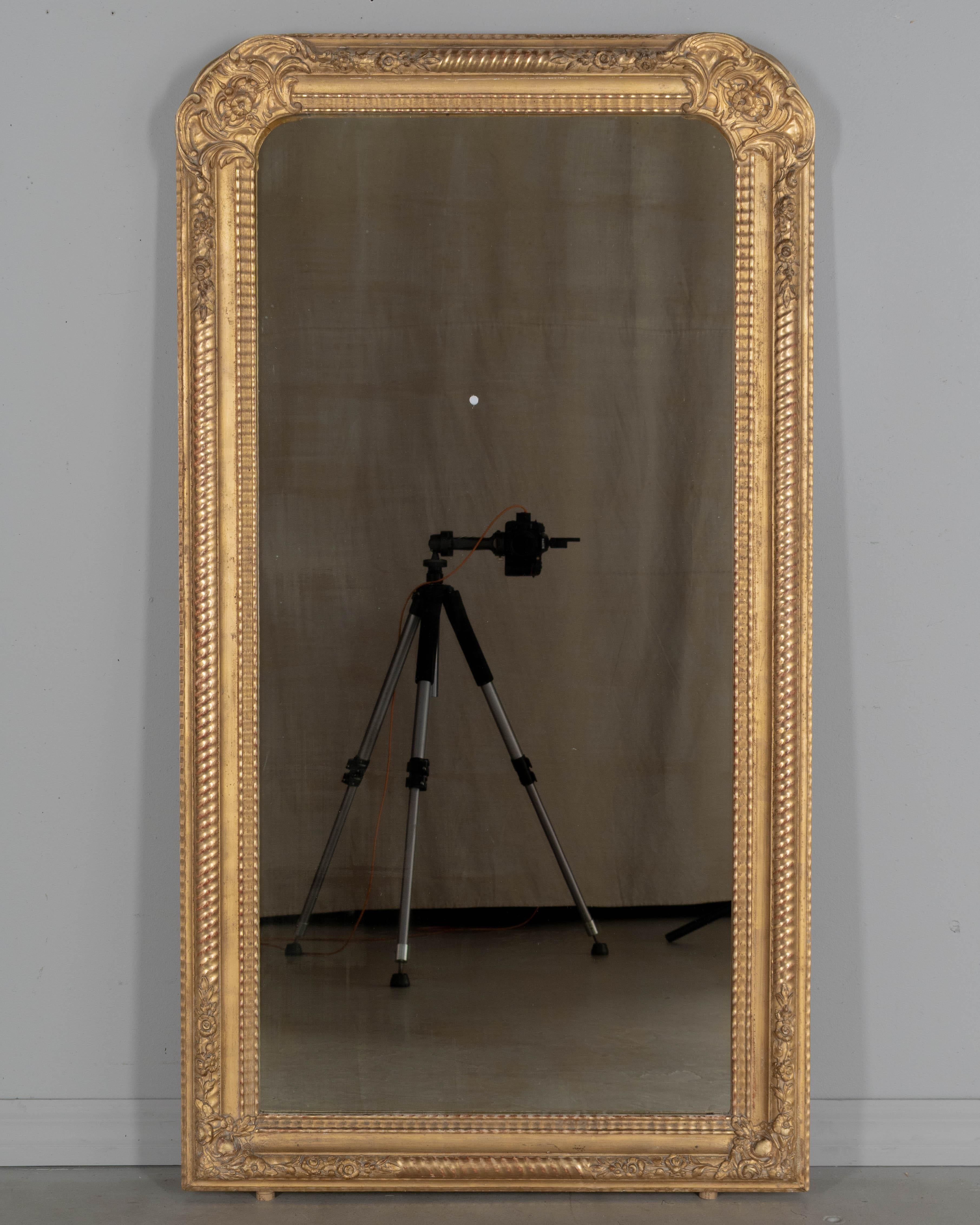 A Louis Philippe French gilded mirror with curved top corners, ribbed pattern and flowers in the corners. Tall elongated proportions. Bright gilt finish is in good condition with minor touch-ups. Circa 1920s
55