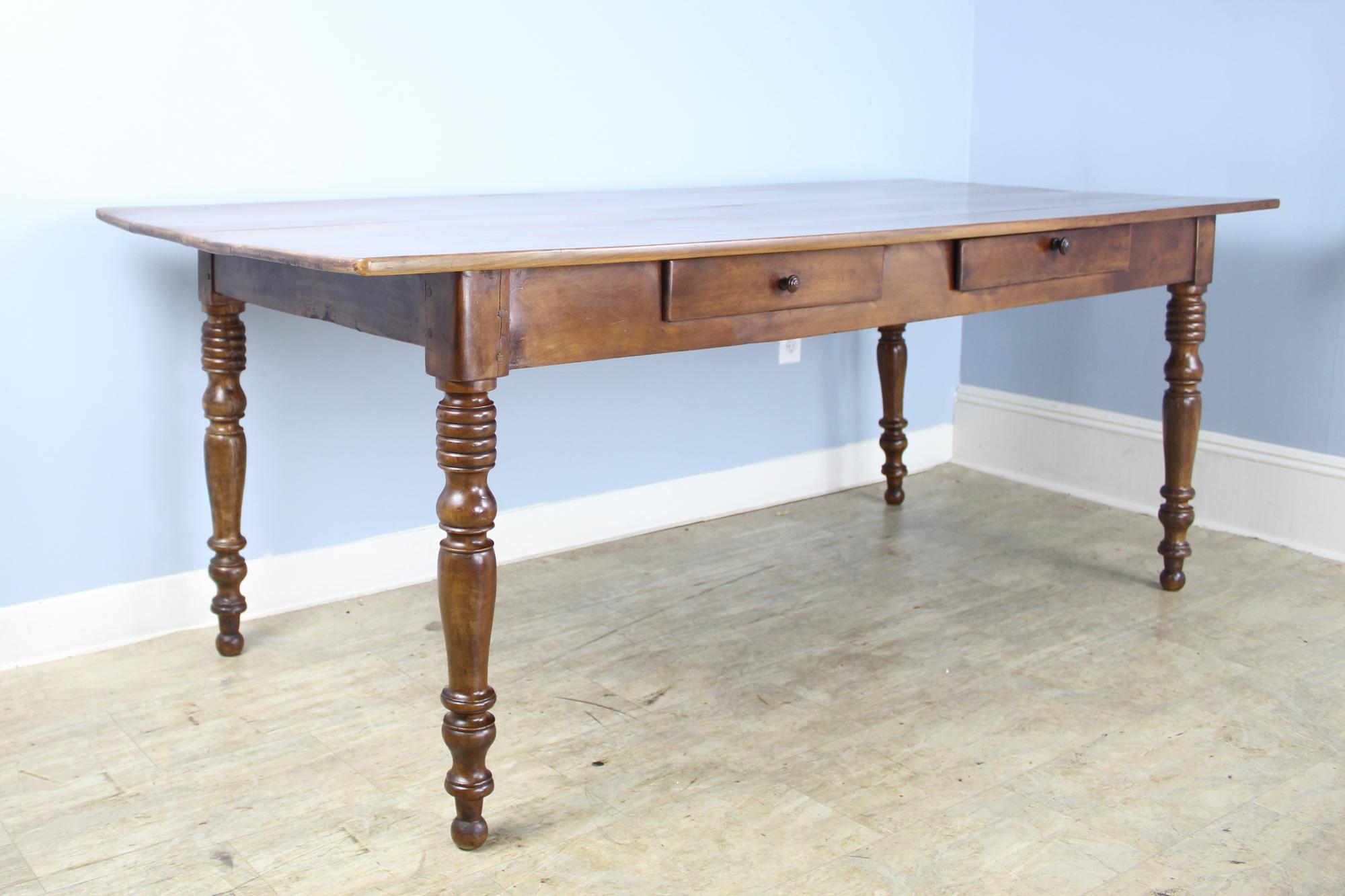 A smaller fruitwood farm table with glossy turned legs and a glorious glowing top. The two drawers in the apron add a note of visual flare and provide some handy storage. There are some small areas of old wear on the top, seen in image #9. 24 in.