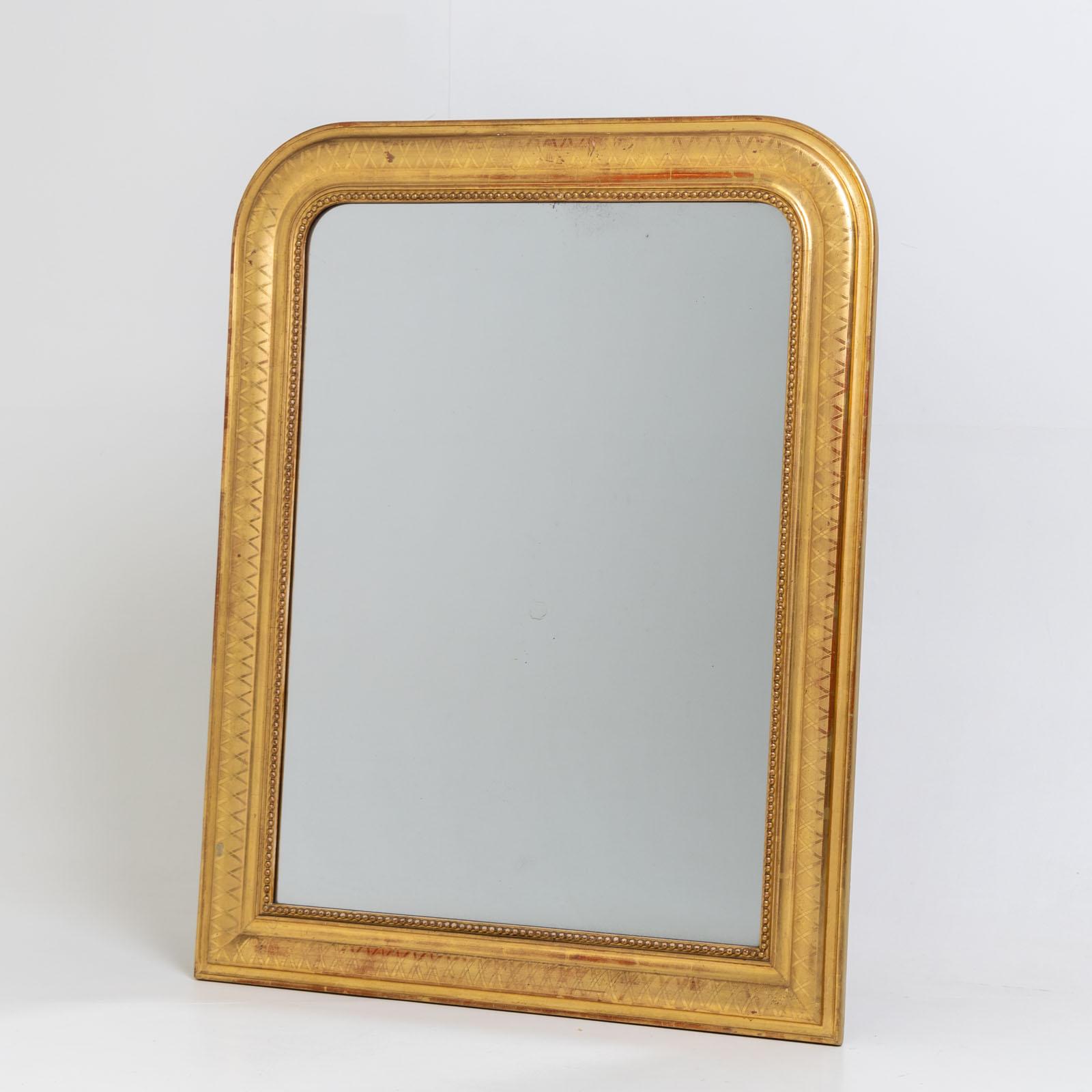 Large gold-patinated Louis Philippe wall mirror with rounded frame and beadwork. The outer groove is decorated with a diamond pattern. The red bolus shines through in places.