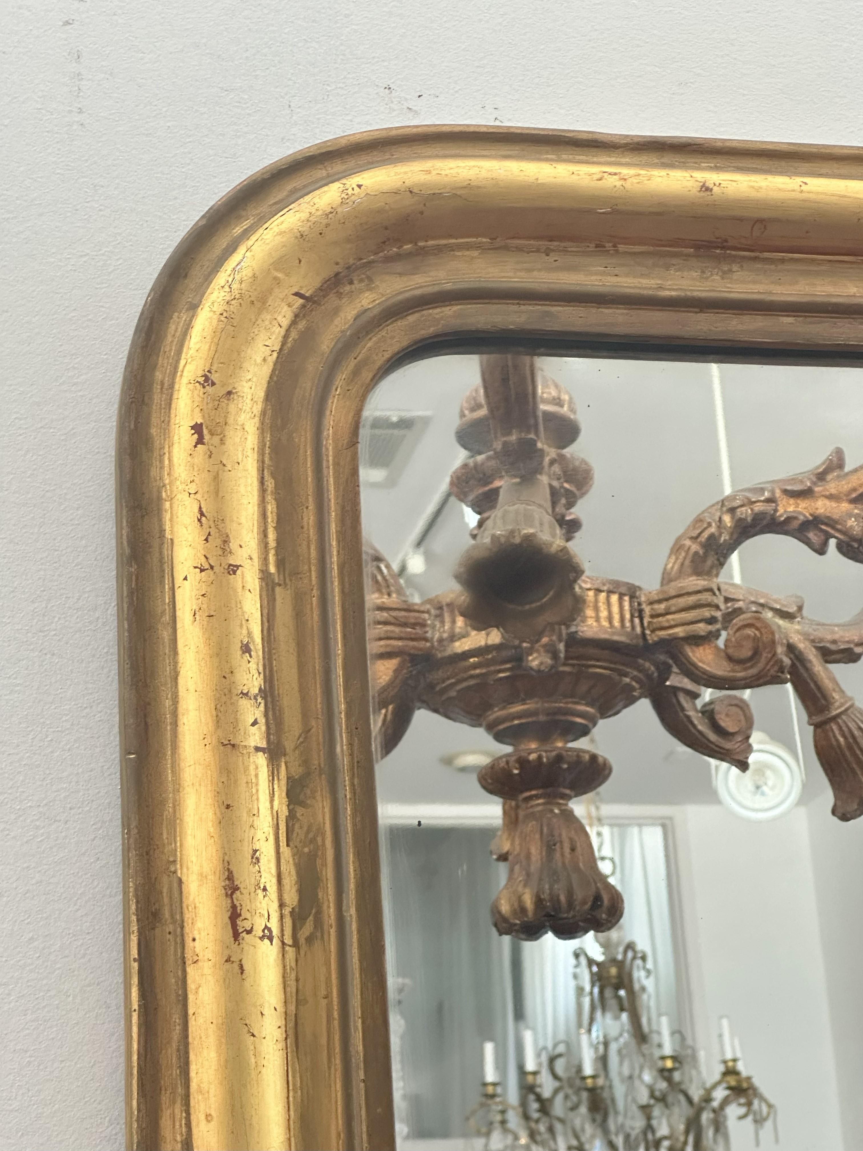 La plaque rectangulaire arquée est entourée d'une bordure moulée en bois doré.