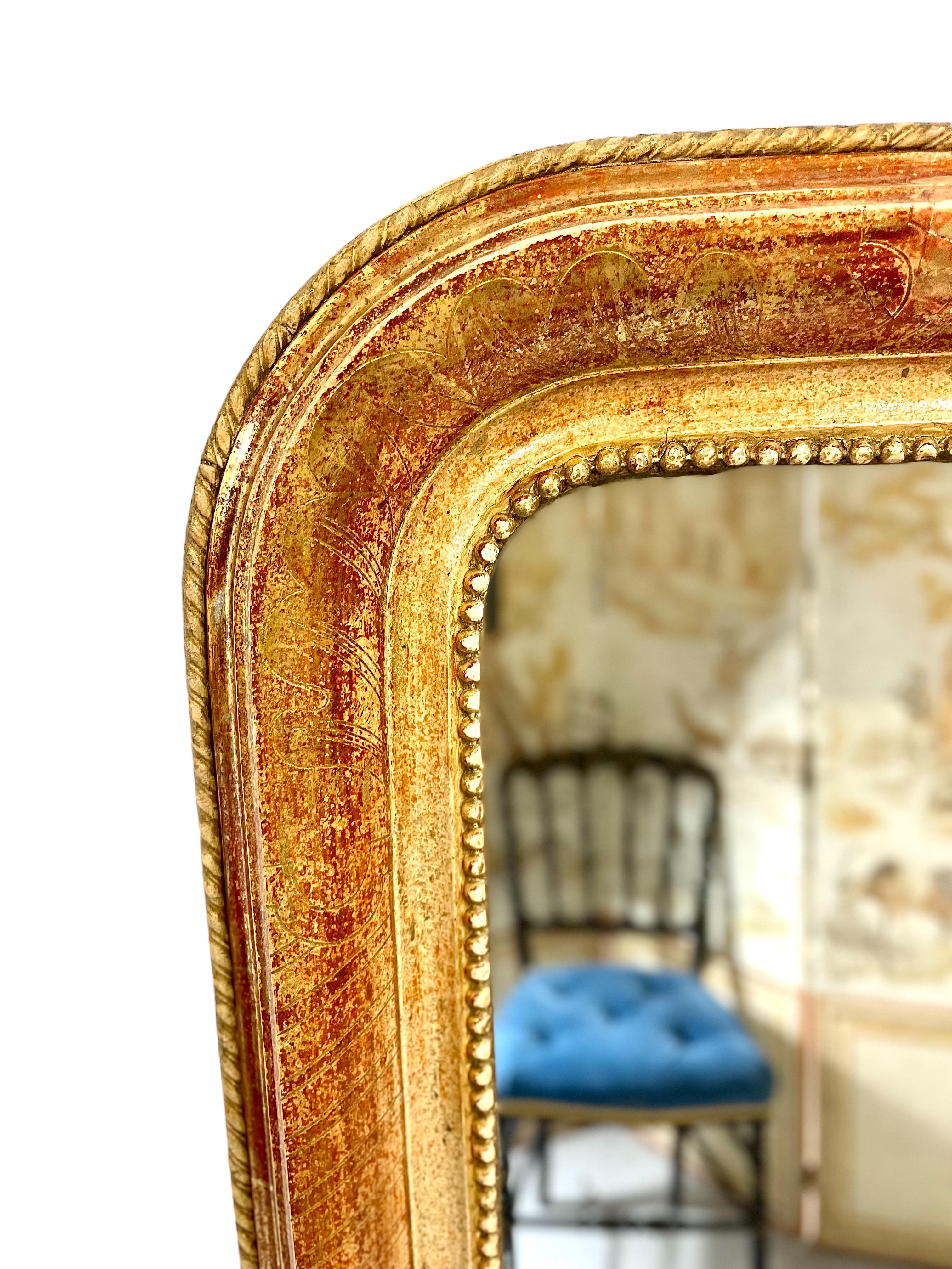 An elegant Louis Philippe giltwood mirror, with the signature rounded upper corners so reminiscent of the period. The frame's inner edge is adorned with a frieze of tiny 'pearls' to enclose the mirror plate, while the four sides are etched with a