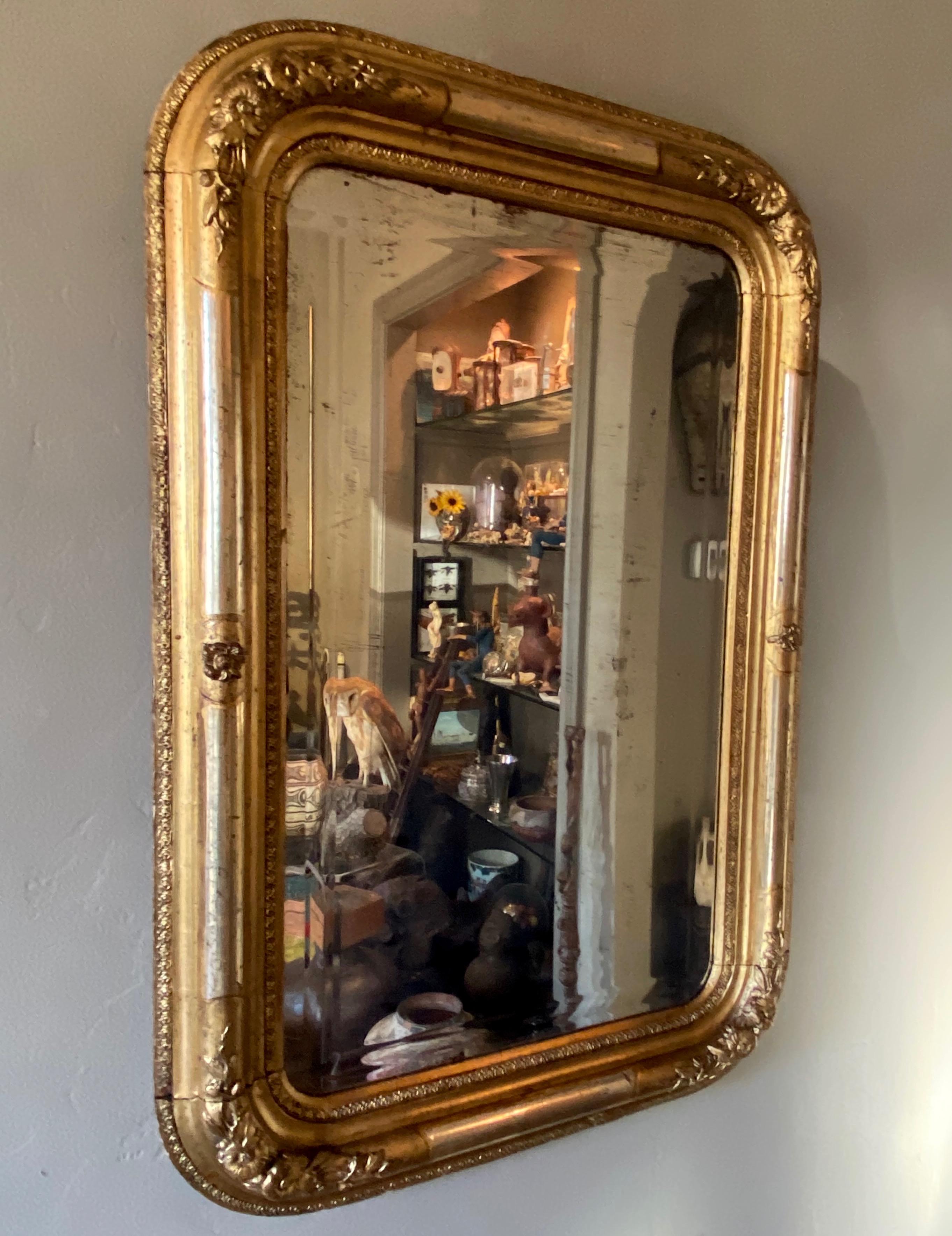 An unusual smaller size Louis Philippe neoclassical style mirror, having gold gilded frame with silver gilt accent and floral decoration at the rounded corners. Wonderful original condition, with original aged beveled mirror.
Easy to use size in