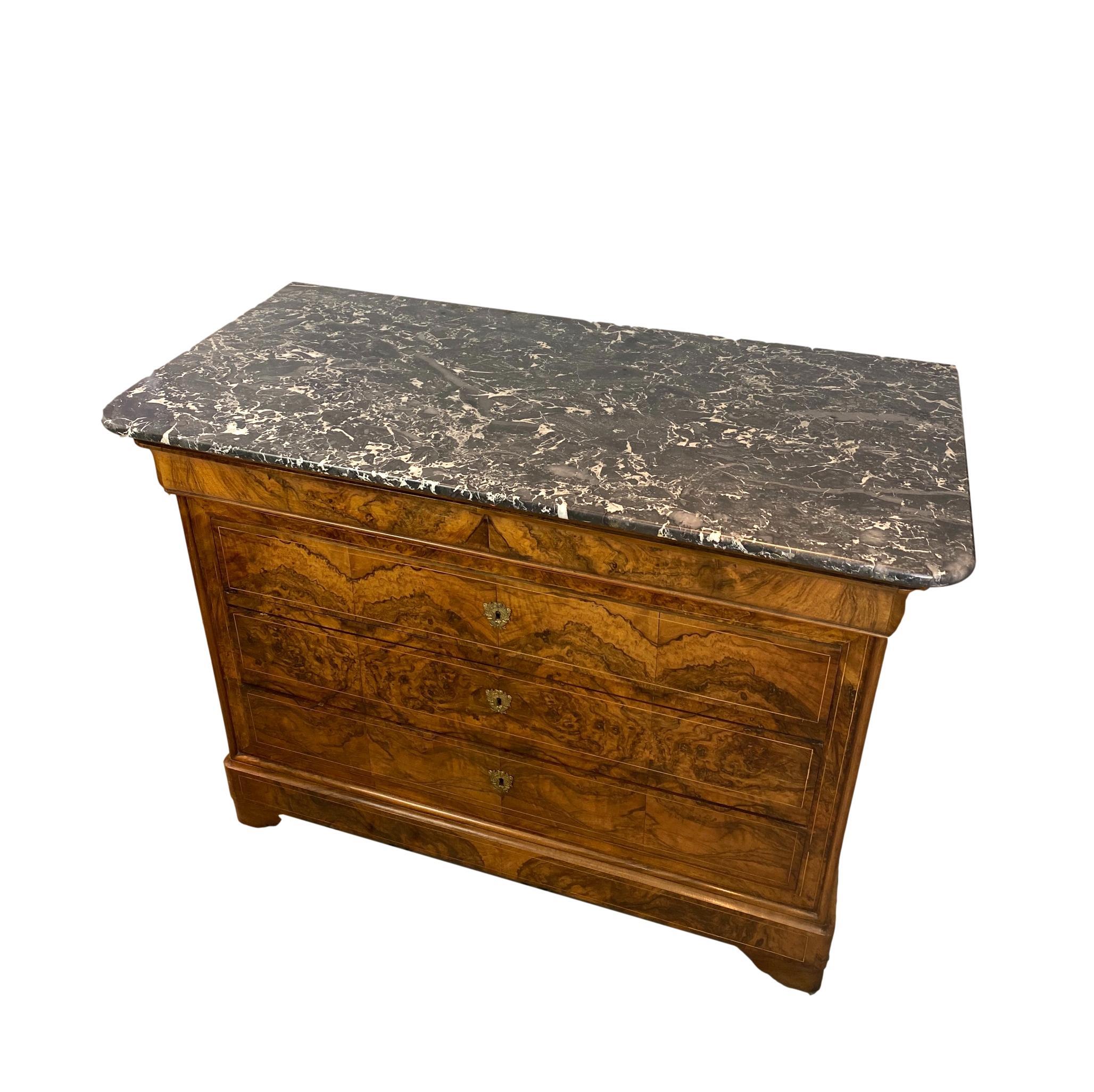 Louis Philippe commode in figured walnut with black and white nero marquina marble top, French,
circa 1840, with a single contoured frieze drawer, over three long drawers with gilt bronze escutcheons, on a conforming plinth base, with shaped