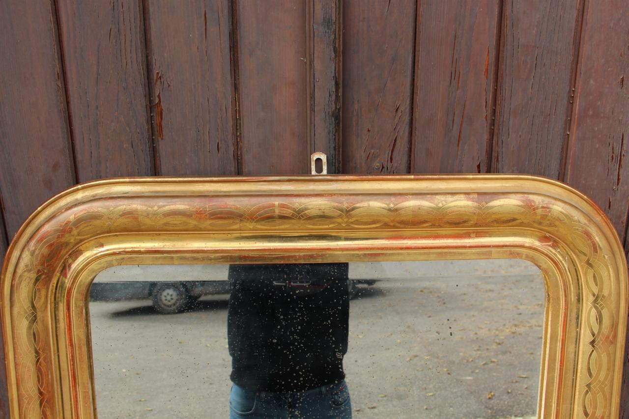 Louis Philippe period mirror in gilded wood with engraved pattern in good condition, beveled mirror on the top and bottom, original parquet flooring on the back