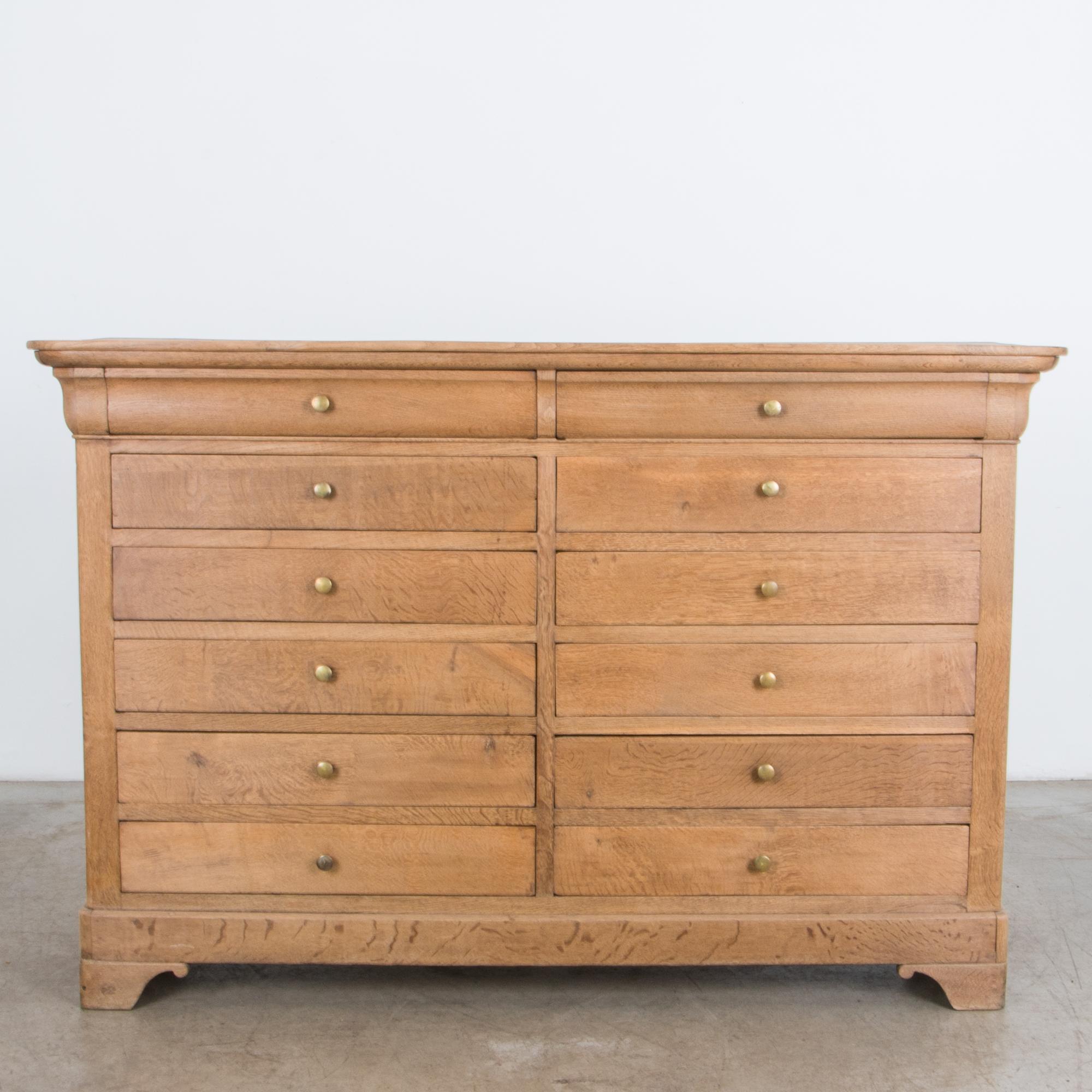 A distinctive drawer chest from circa 1880 France in distinctive curly oak. An elegant shape is simple yet refined, with clean lines and subtle ornament; a flared top, simplified scroll legs. A unique large format features twelve drawers, with