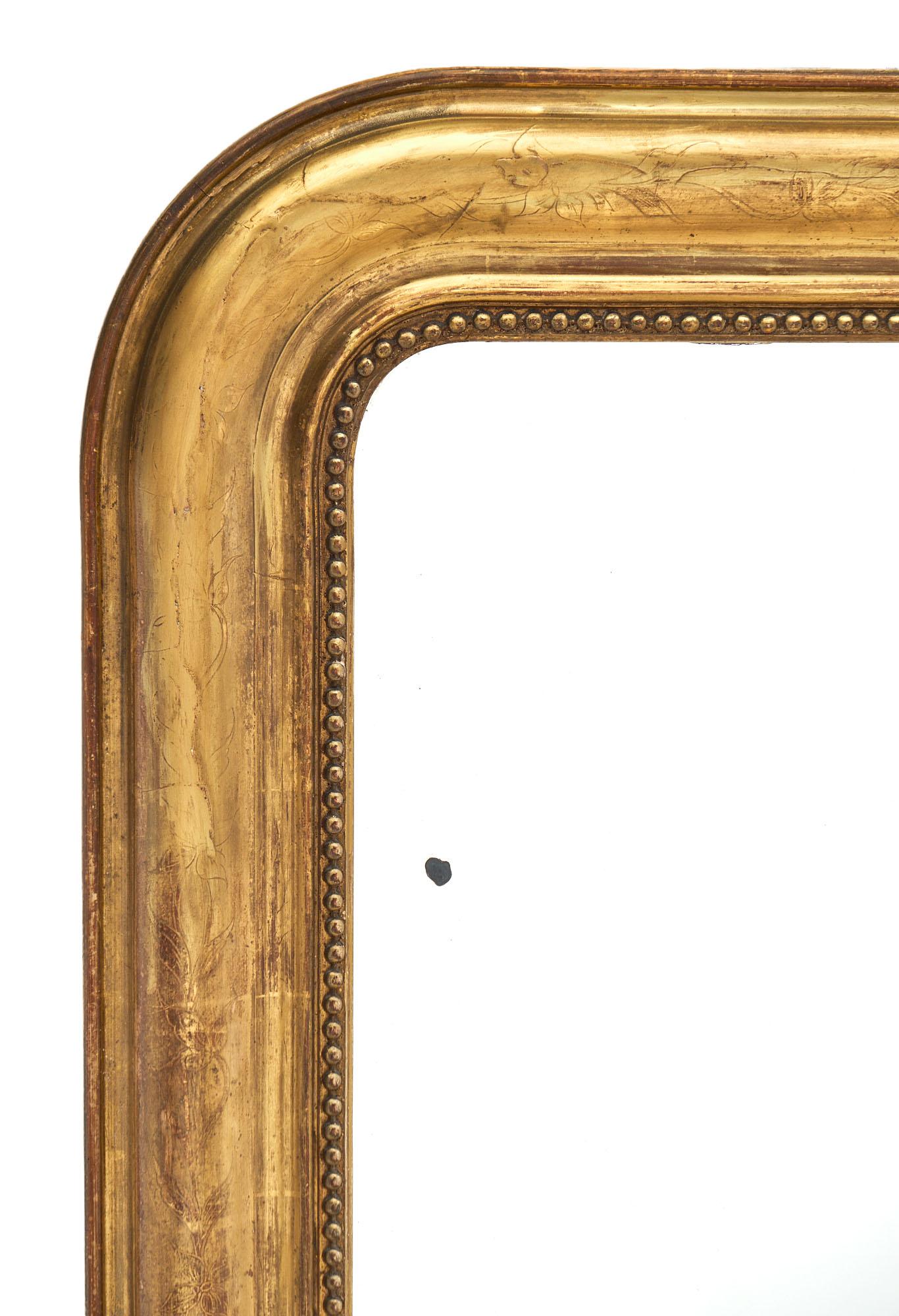 Antique Louis Philippe period French mirror with gold leafed frame, hand engraved floral details, and original mirror.