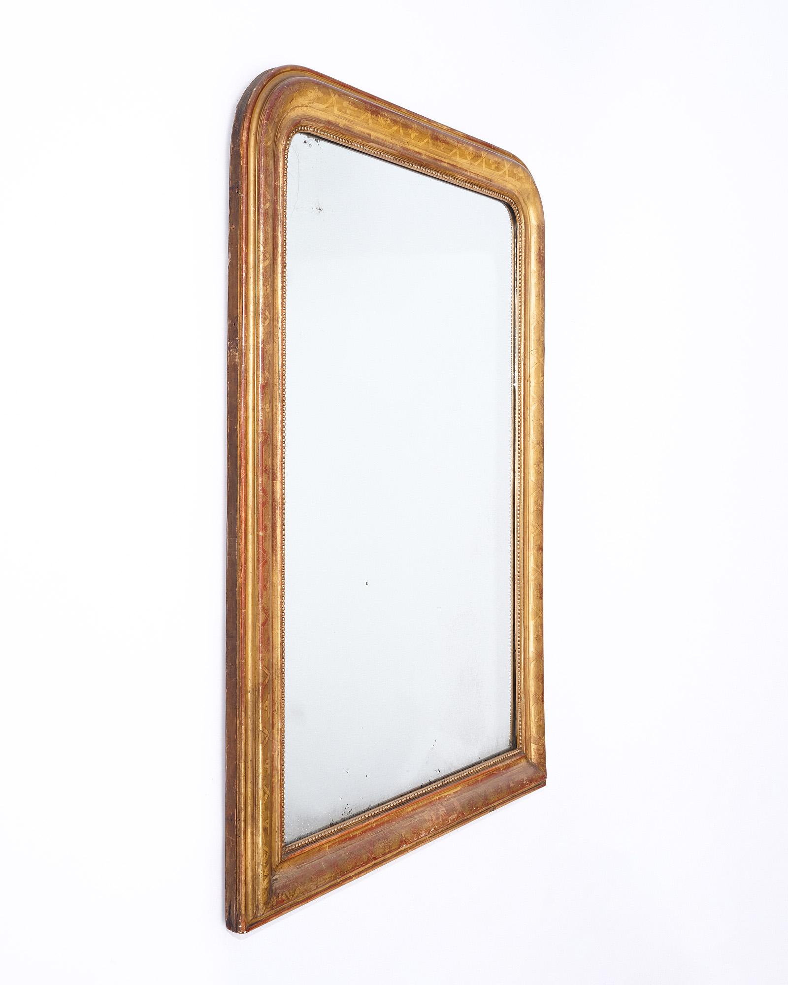 Mirror, French, from the Louis Philippe period. Original mercury “diamond dust” mirror. The frame is made of solid wood hand carved and stuccoed, the mirror boasts floral chiseling and an undertone sienna glaze covered with a patinated 24 carat gold