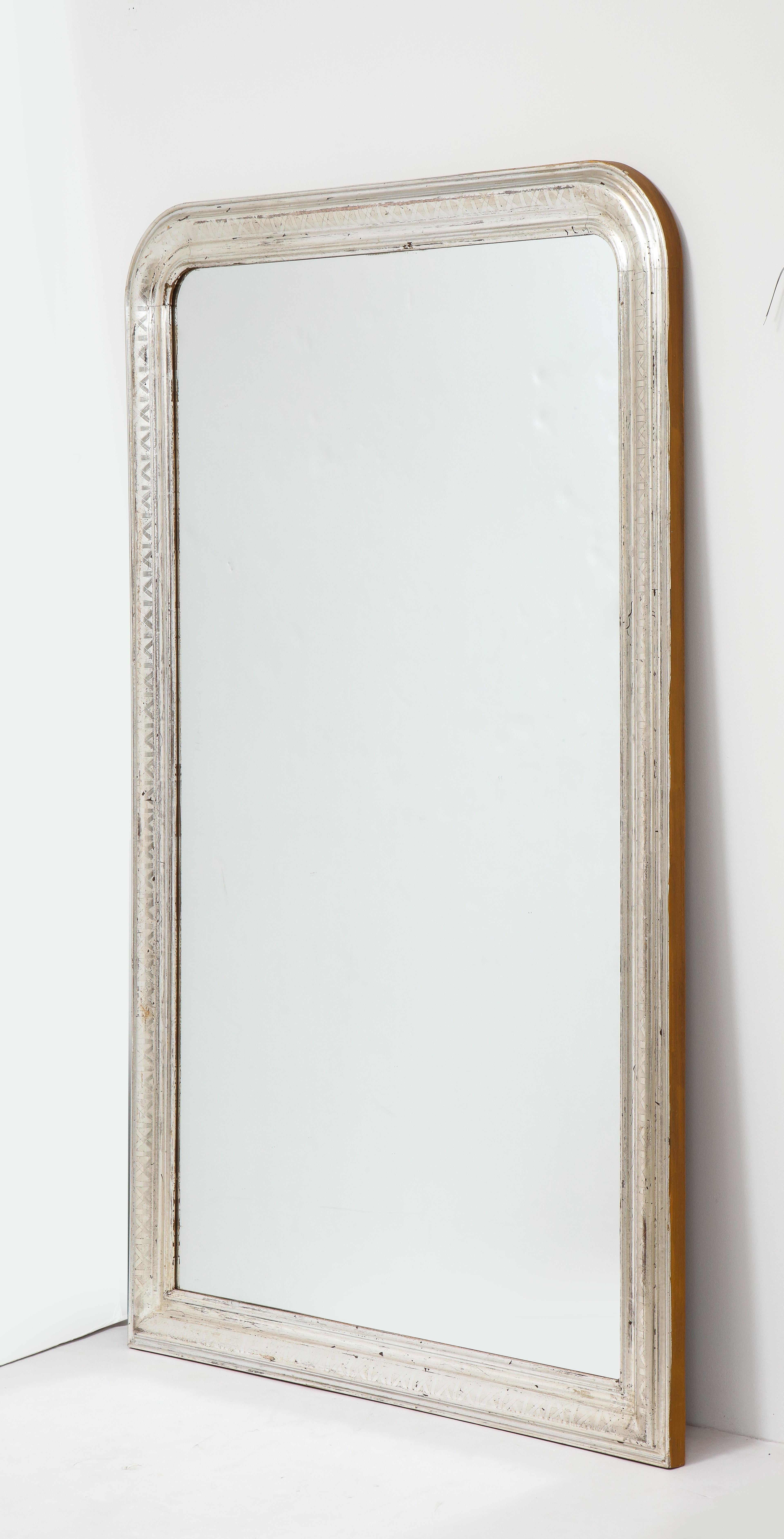 Brilliant Louis Philippe wall mirror with silver gilt frame made in France late 19th century. The frame has rounded upper corners that are typical of the Louis Philippe style. The mirror plate has been replaced. Generously sized, this statement
