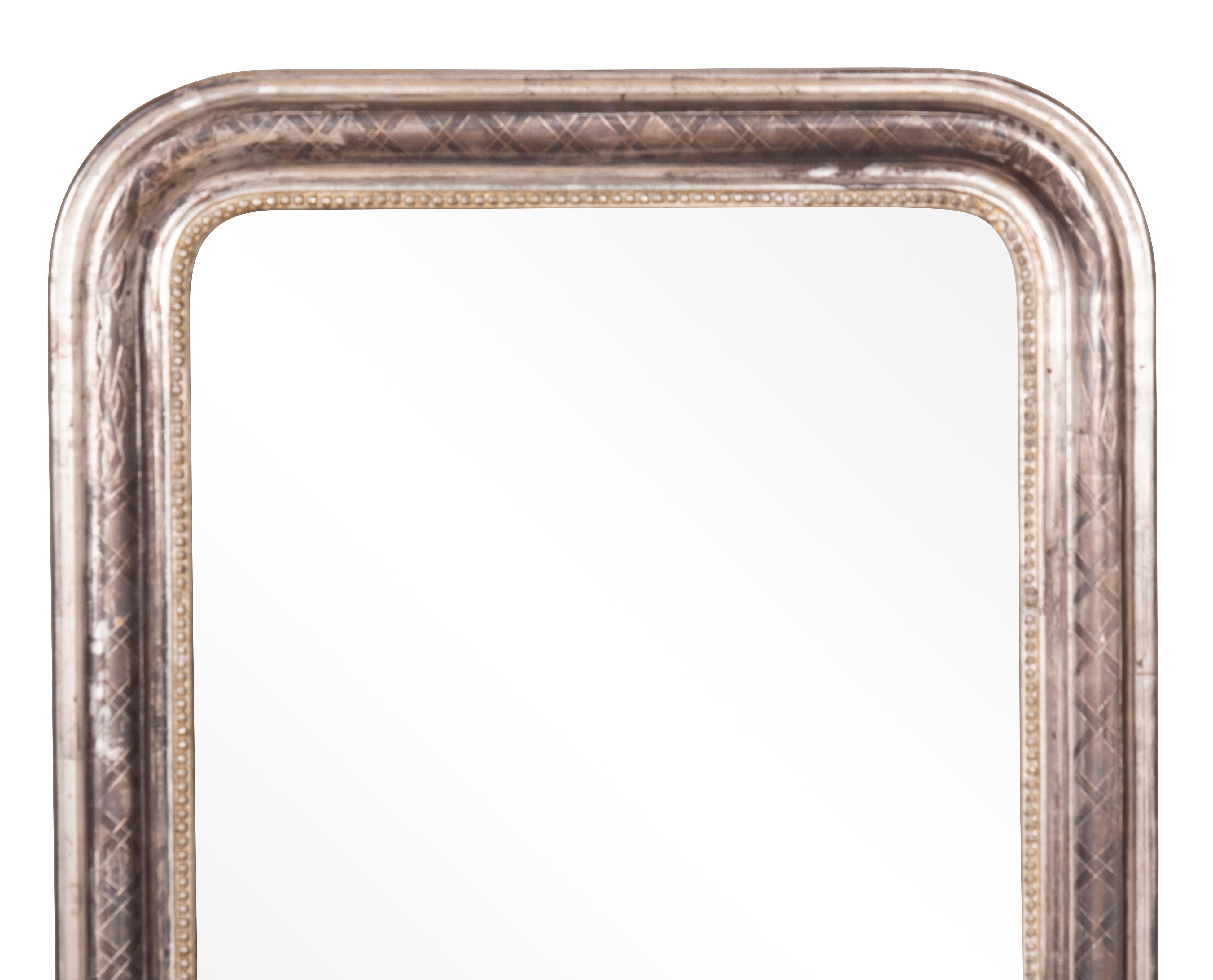 Rectangular with rounded top corners. Molded oxidized silvered frame with etched decoration and beaded inner edge.