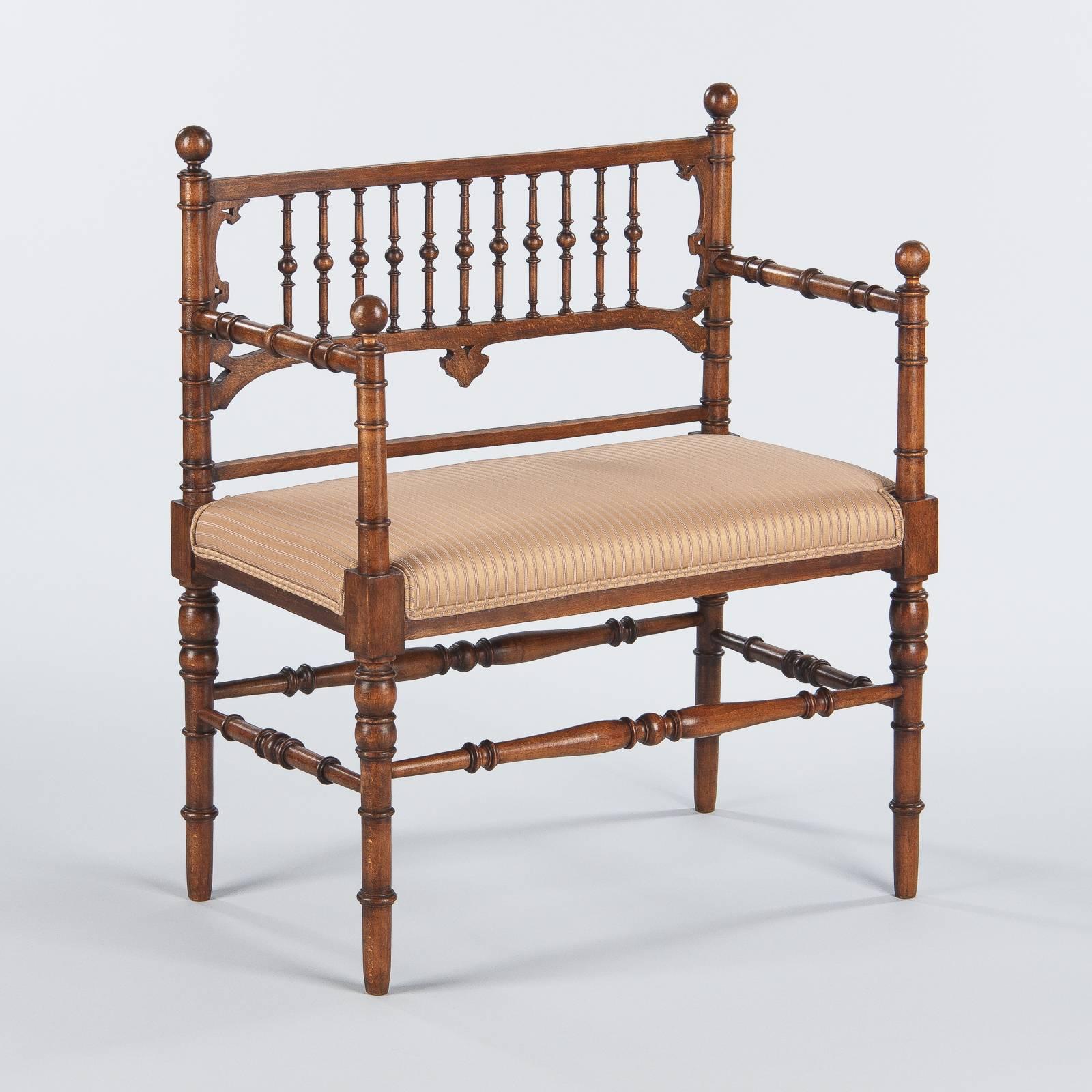 Diminutive walnut bench with upholstered seat in the late Louis Philippe style, circa 1900. Perfect in stature for a child, this charming bench features beautiful woodwork and a wonderful patina. Turned legs and stretchers in simple baluster form