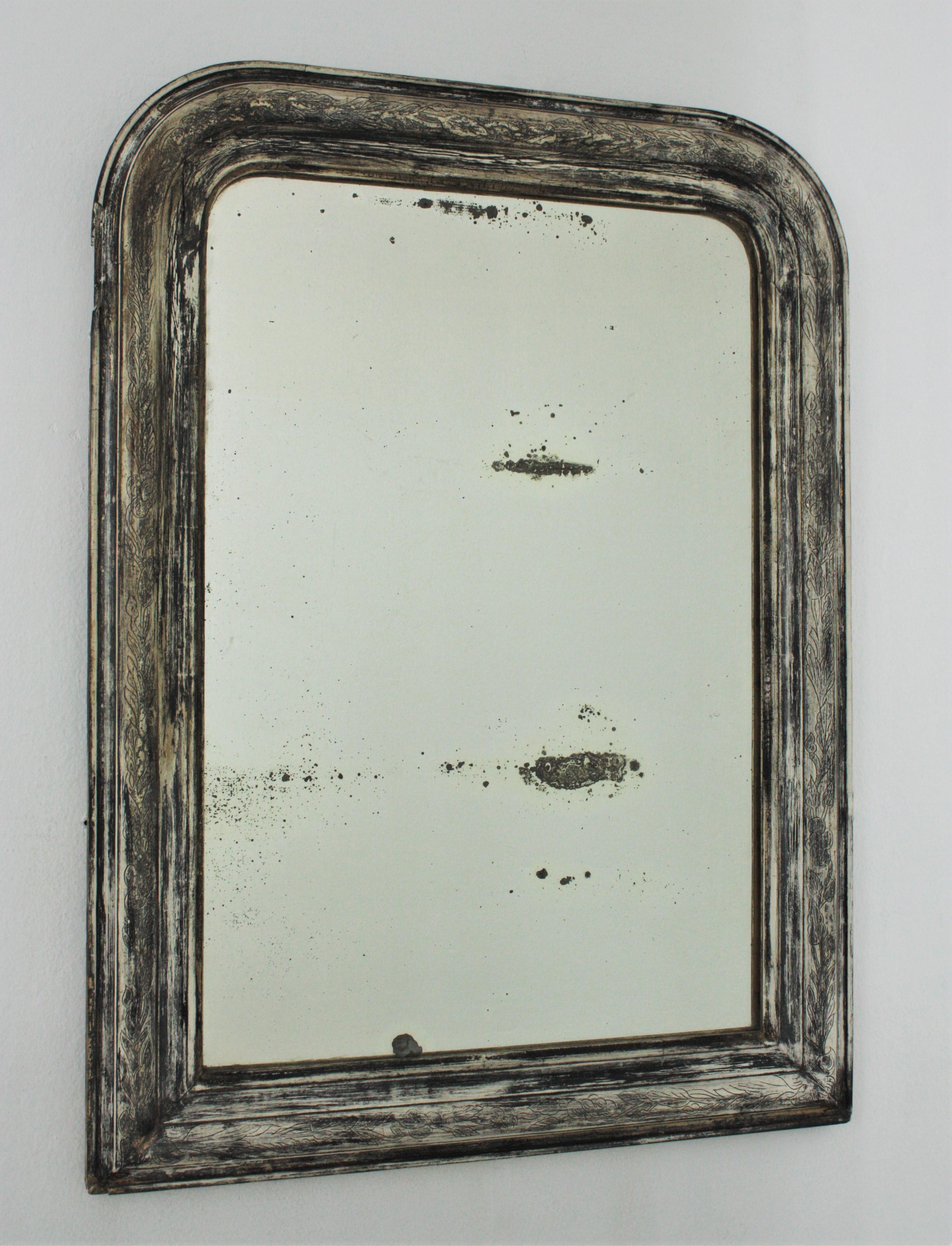 French 19th century Louis Philippe mirror in grey and white patina with silver leaf accents.
This antique mirror has a beautiful frame with engraved flower details and an interesting patina in grey and white colours retaining rests of silver