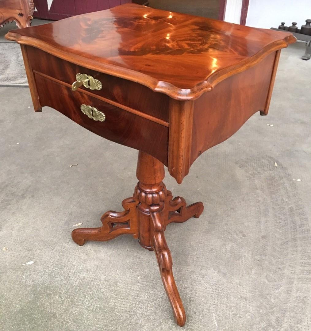 This is an antique Louis Philippe walnut sewing table with brass fittings from Paris. The walnut wood has a unique symmetrical bookmatched veneer in a dark brown colour. It has been hand polished with shellac and polished to a high gloss to bring