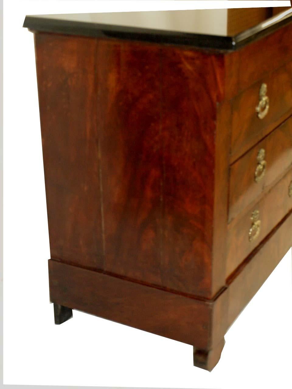 French Louis Phillipe four drawer commode with thick black granite top ( not original ) , the top drawer, as is typical, has no hardware, all drawers and sides with beautiful mahogany veneer, intricate brass pulls and escutcheons, warm color and