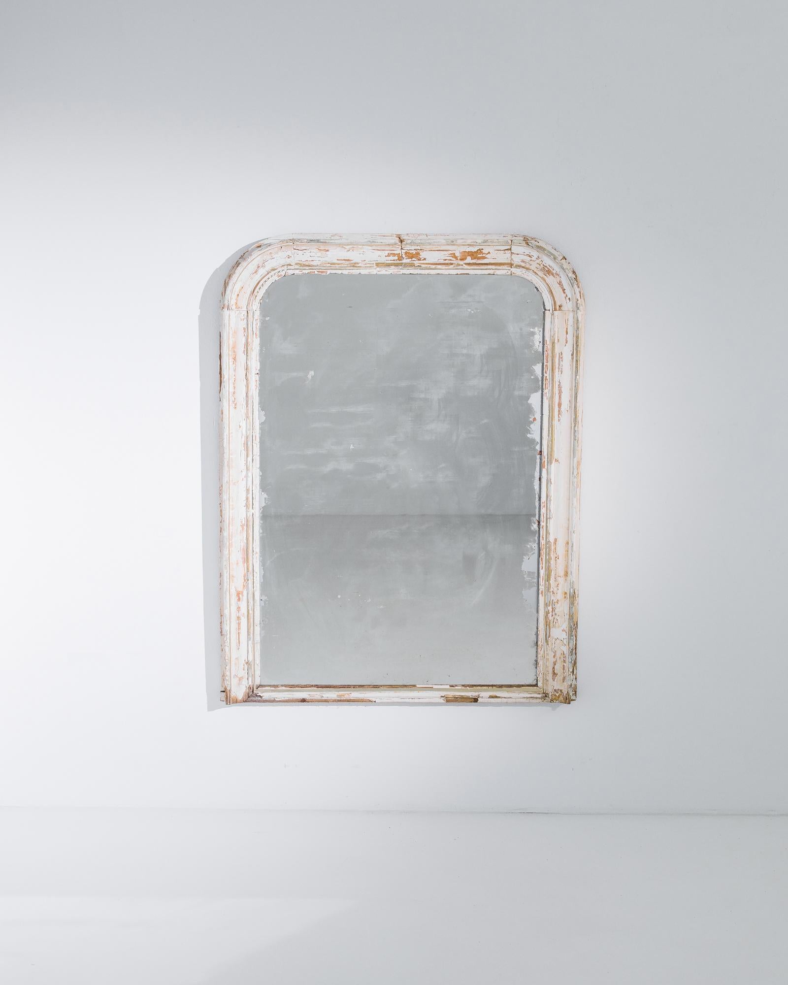 A white patinated wood framed mirror from France, produced circa 1880. A simple arch of glass, is a distinct feature of the Louis Phillipe style, set in a deep frame of milky white wood. Chips in the original patination, and a sliver of silver