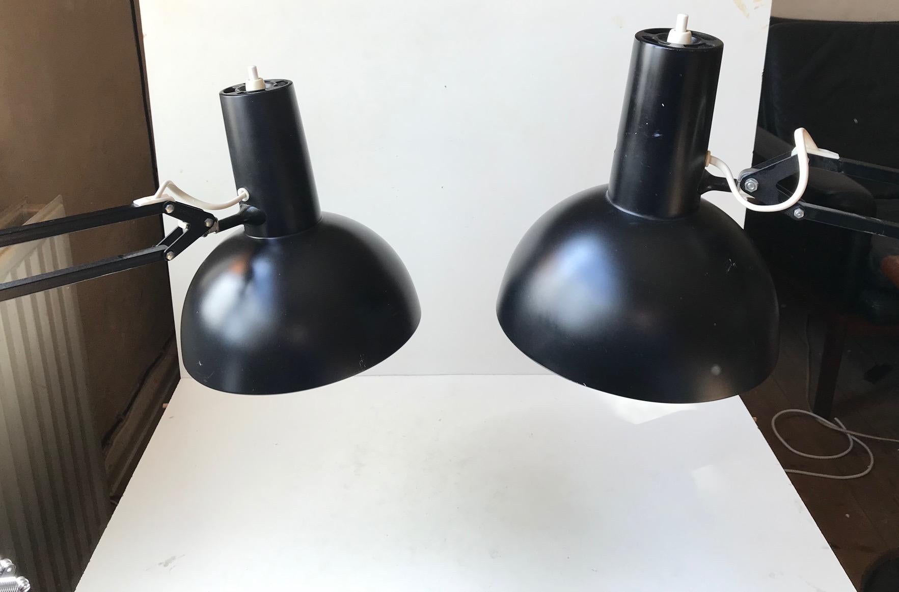 Often referred to as 'The Ghost of PH' and based on the Ideas of Poul Henningsen these fully adjustable black 'Anglepoise' desk or wall lights was designed in-house at Louis Poulsen in the early 1970s. Both with early LP stickers and porcelain