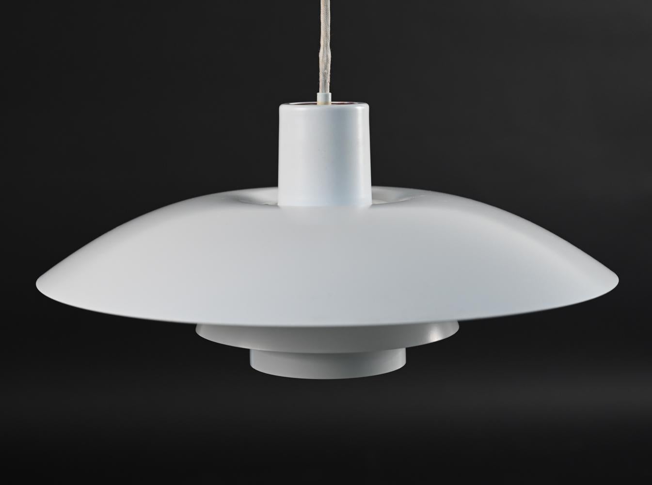This pendant light was designed was Poul Henningsen for Louis Poulsen as part of Henningsen's groundbreaking three shade system that uses metal shades to direct uniform, downwards lighting. This model PH 4/3 pendant light has a clean, modern look