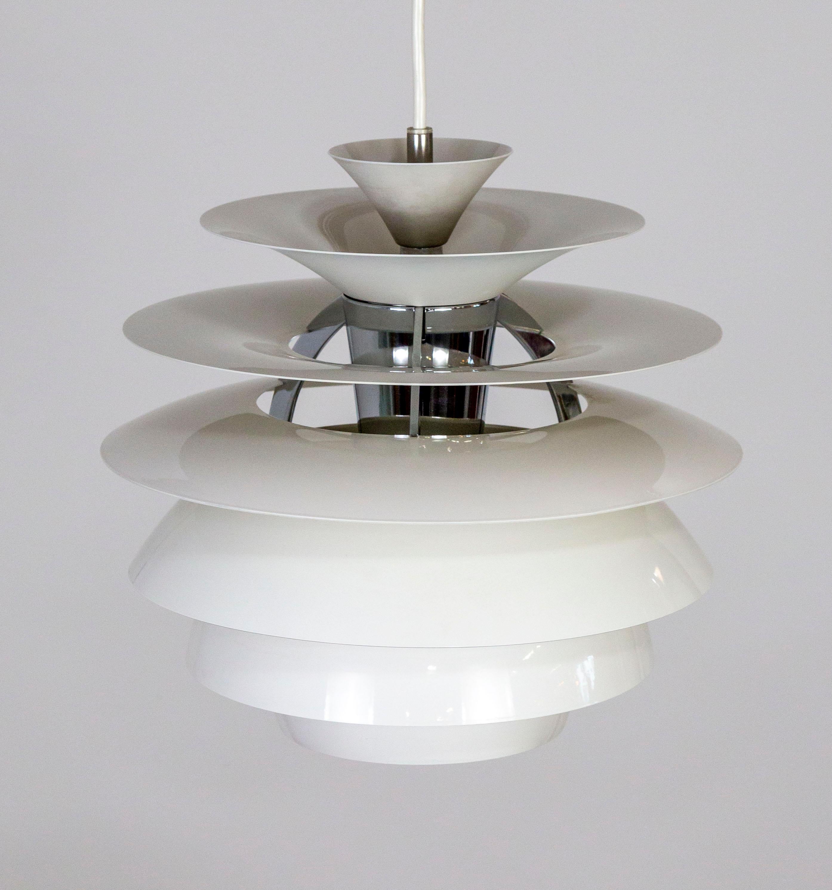A pendant light that was originally designed in the late 1950s by Poul Henningson for Louis Poulsen in Denmark. This piece is from the relaunch in 1982. The light is composed of tiers of arcing aluminum shades around a chrome inner cylinder. The