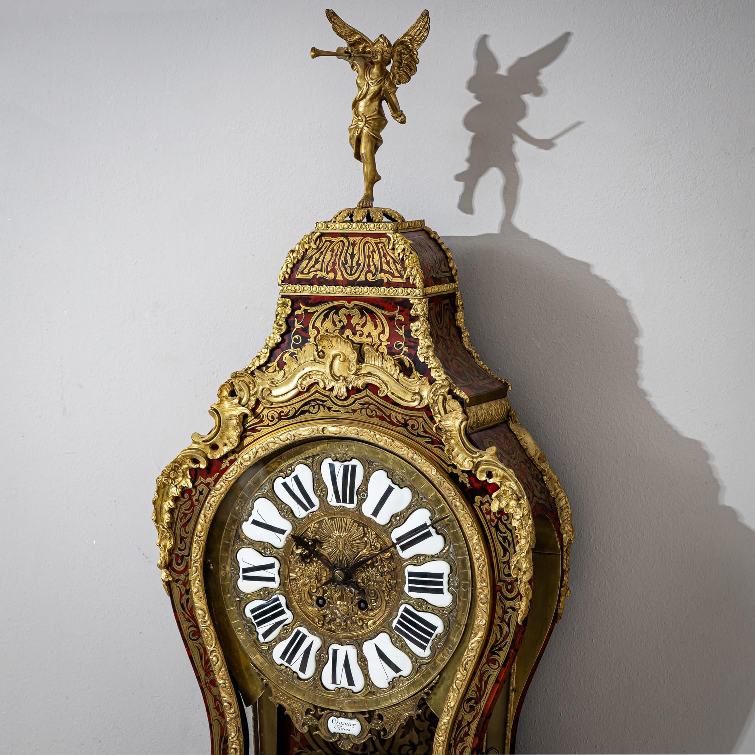 This magnificent Louis XV-style pendulum clock from the mid-19th century features elaborate Boulle marquetry and fire-gilded bronze appliqués in the form of rocaille, shell decorations, peacock motifs, and espagnolettes. The case is crowned by a