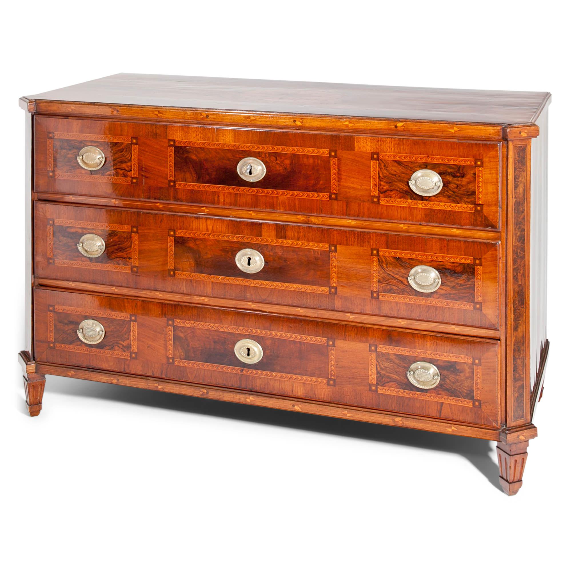 Three-drawered Louis Seize chest of drawers in walnut and burl wood veneered. The commode stands on fluted and tapered feet and has slanted corners. The top shows a beautiful flower-shaped marquetry in a medallion. The chest was professionally