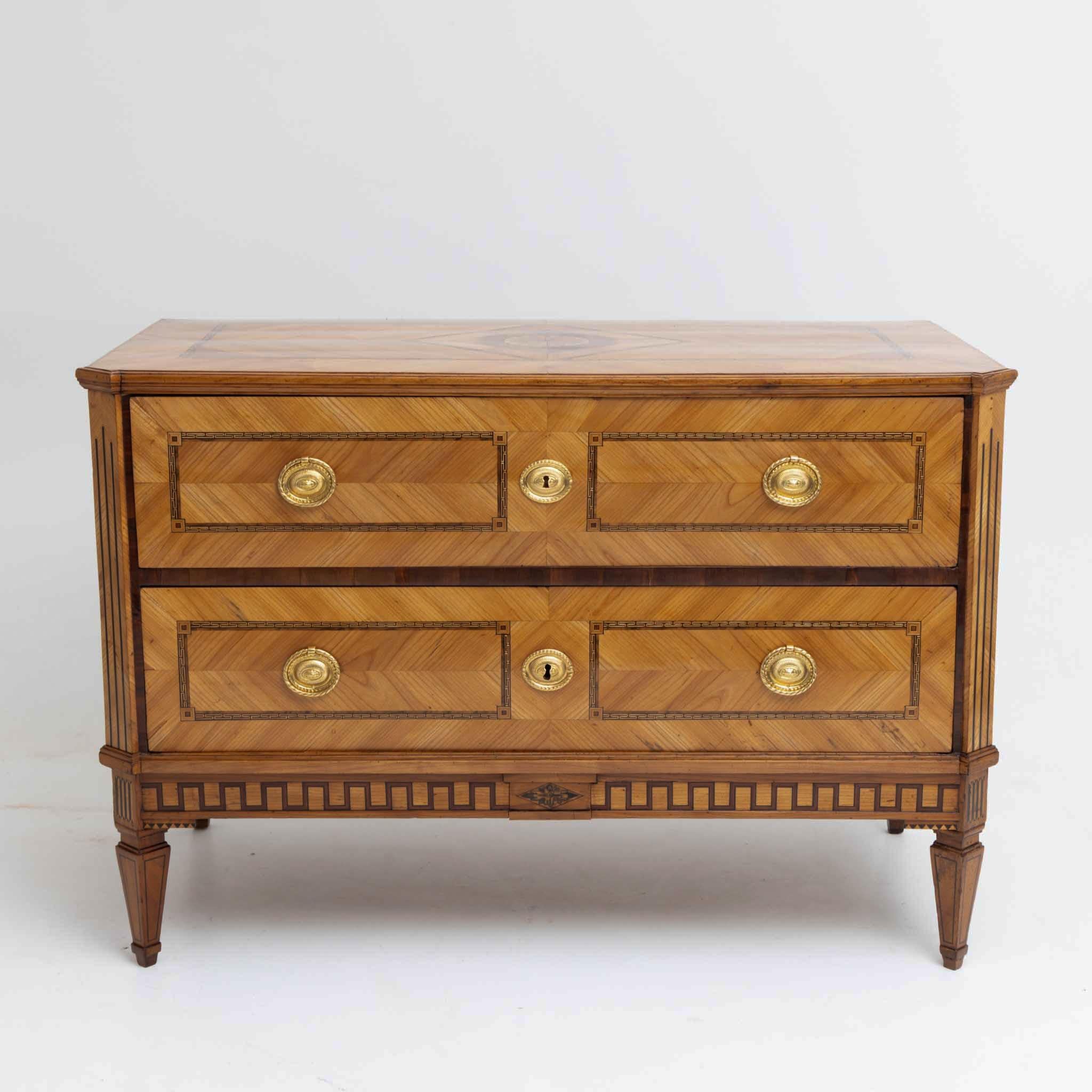 Louis Seize chest of drawers with beveled corners and two drawers. The dresser stands on square tapered feet and shows inlay work in the form of meander and filling fields on all sides. The dresser has been restored and hand polished.