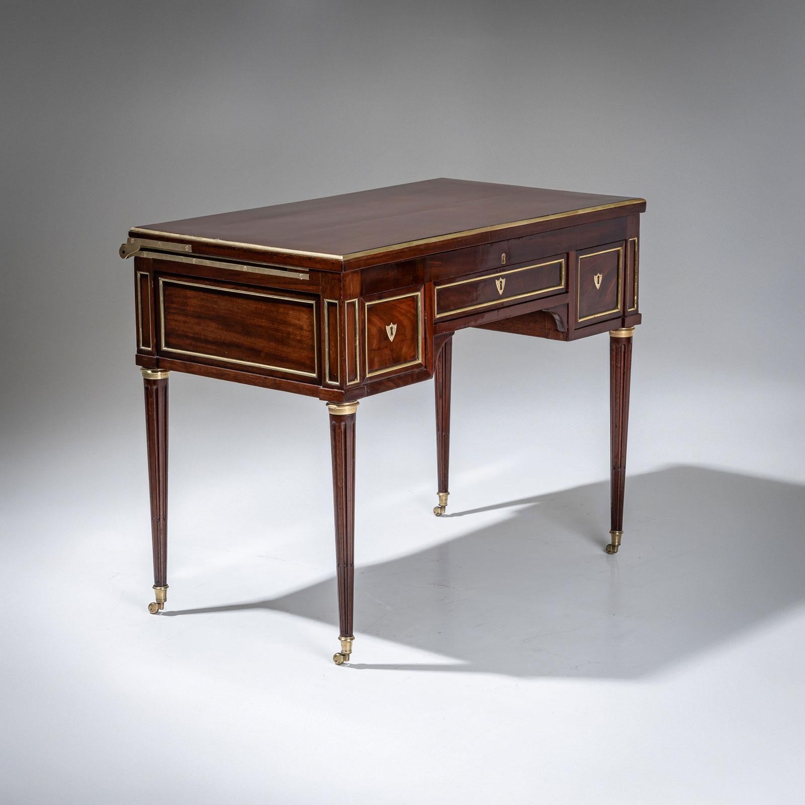 A cleverly designed Louis XVI vanity or dressing table. The piece, which can also be used as a desk, is made of mahogany and stands on conical fluted legs with brass castors. The table top is attached with a sliding rail and reveals a white marble