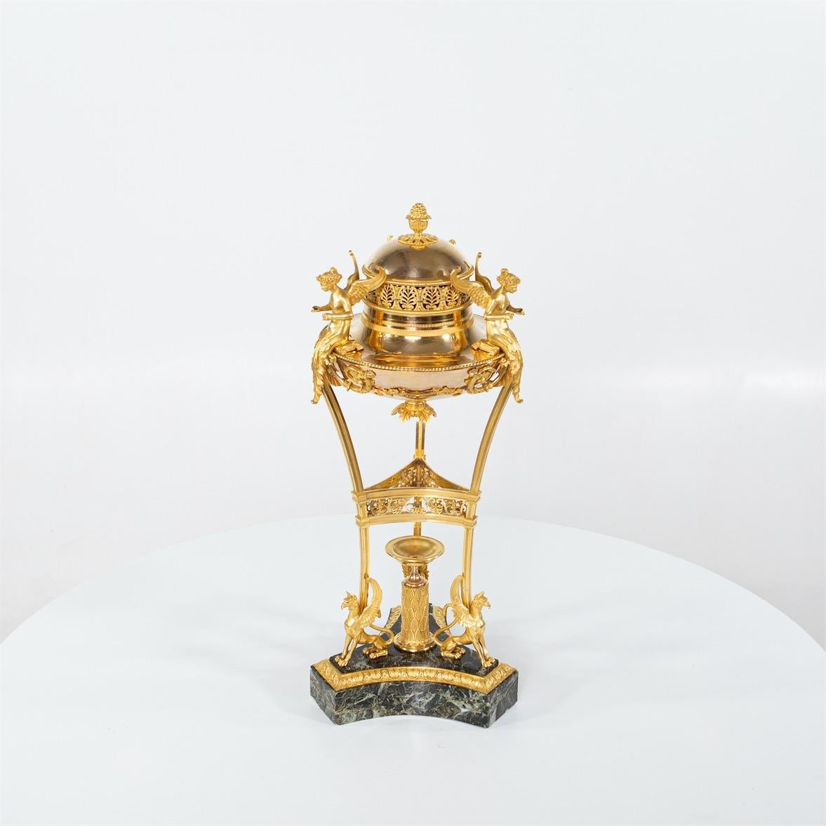 The masterfully crafted brûle perfume stands on a green marble trefoil base. On this pedestal, a round 