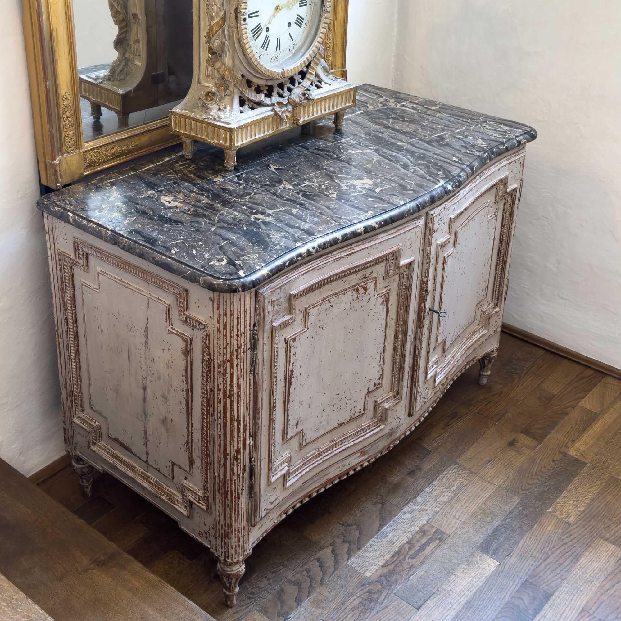 Two-door sideboard with a slightly convex front and a beautiful original marble top in a dark grey color with lighter colored veins. The corpus is coffered on all sides and has decorative friezes. The corners are rounded and fluted and merge into